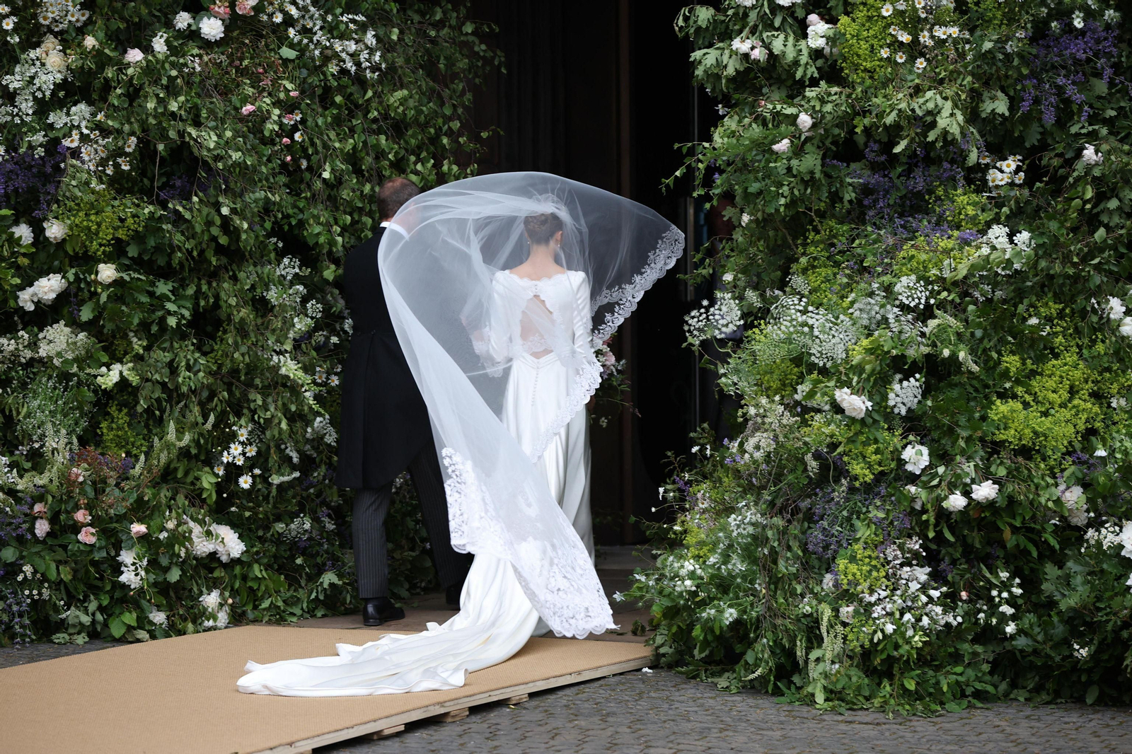El velo de la novia se levanta con el viento al entrar en la catedral