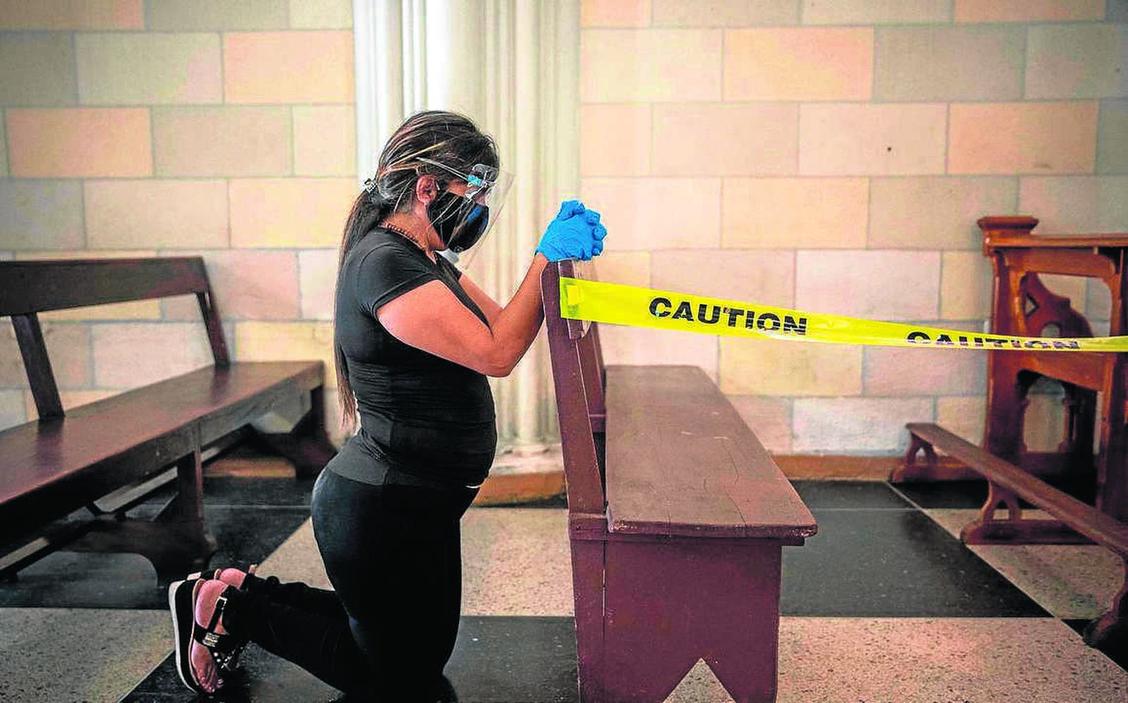 Una mujer con mascarilla y guantes en una iglesia