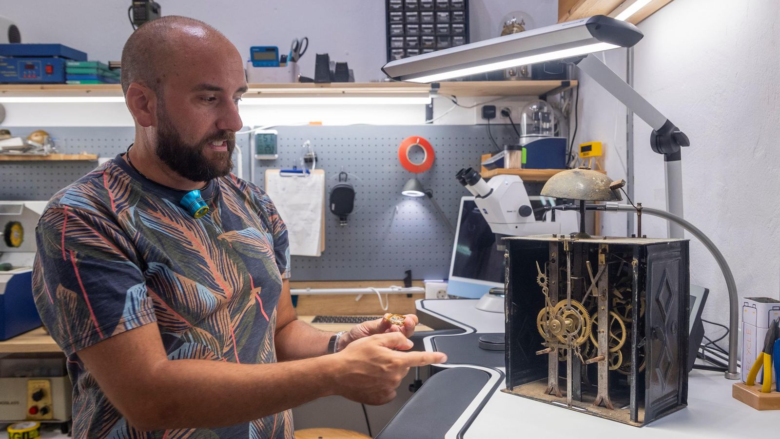 Jesús Moreno muestra el interior de un reloj de carrillón que está reparando.