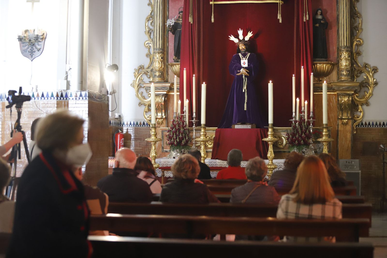 El Señor Cautivo de San Pedro, en su altar, mientras varias personas le rezan durante el primer viernes de marzo.