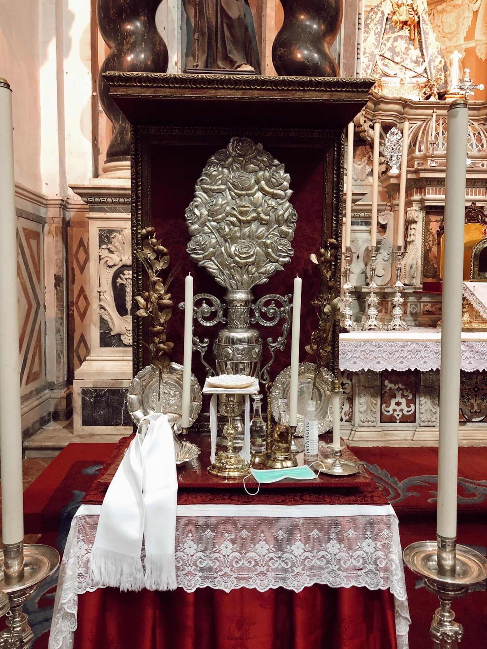 Mascarilla entre los elementos litúrgicos en una de las credencias del altar de La Cena por Cristo Rey.