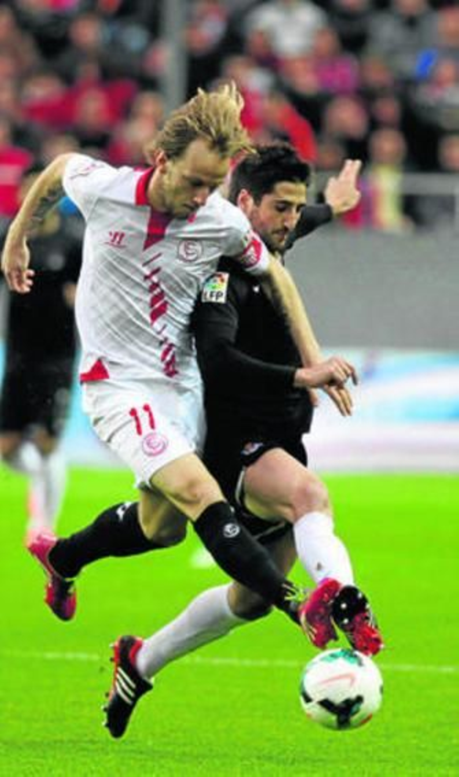 El sevillista Rakitic disputa el balón con Markel Bergara.