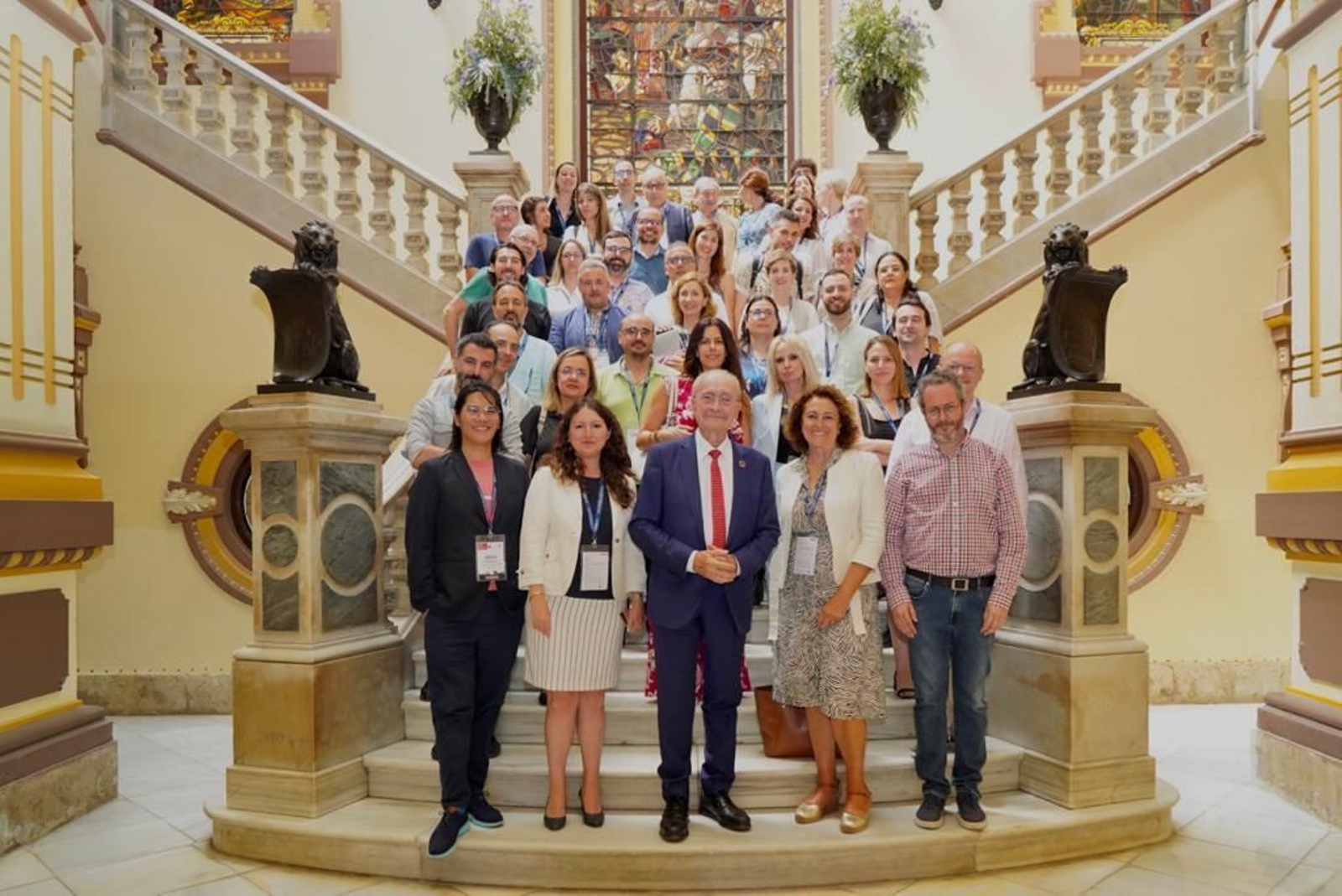 Organizadores y participantes en el evento posan junto al alcalde en el Ayuntamiento.