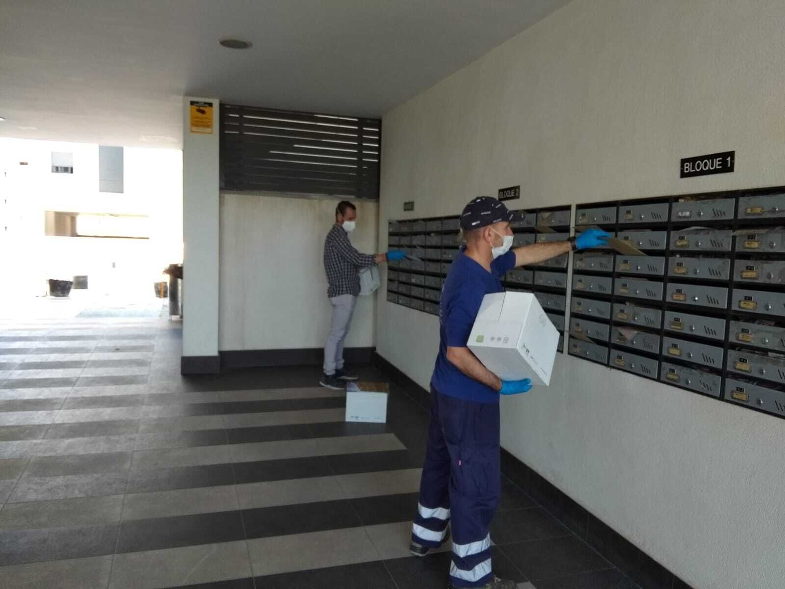 Trabajadores municipales depositas los sobres con mascarillas en buzones