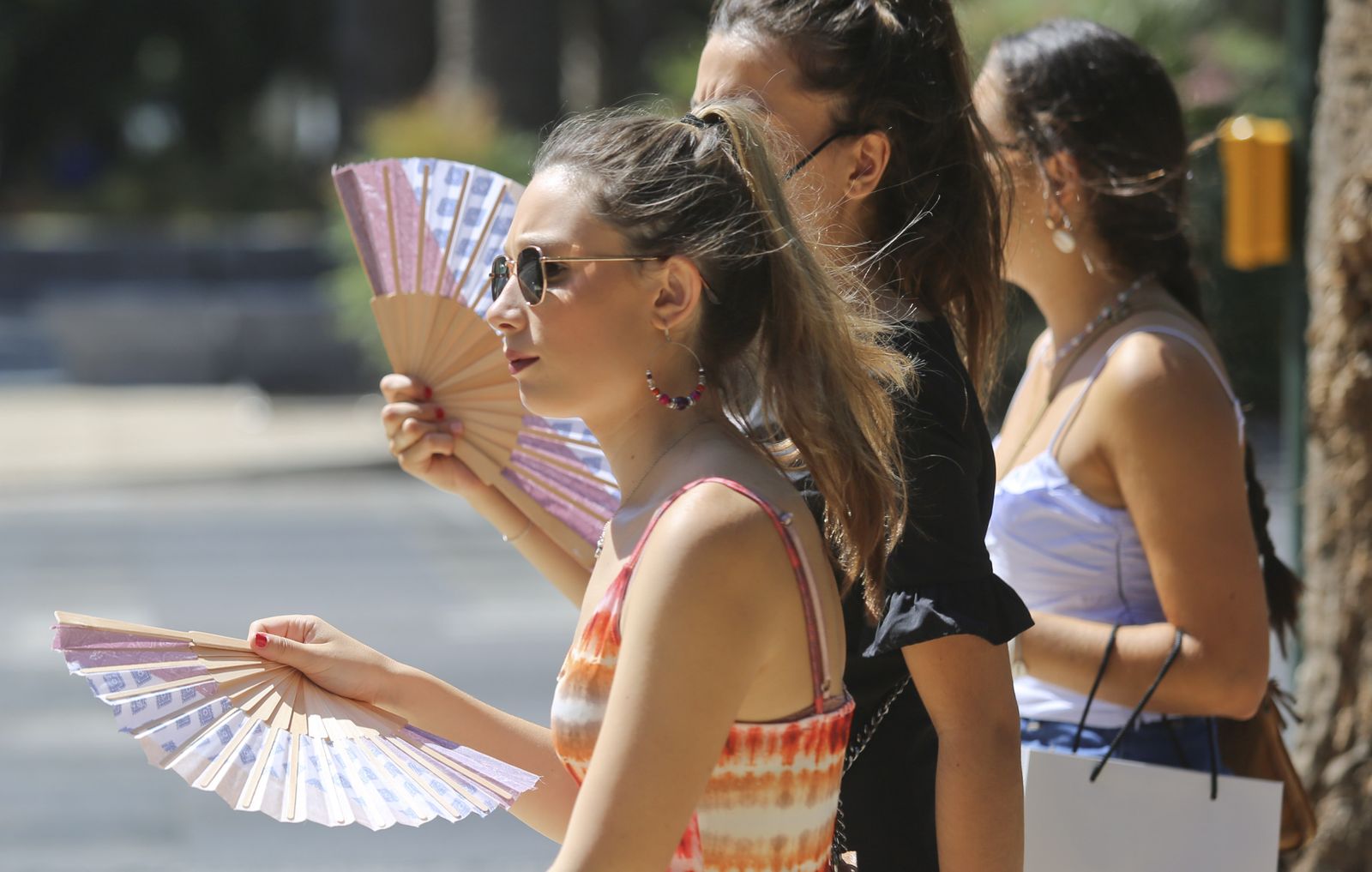 Varias jóvenes con un abanico por la capital.