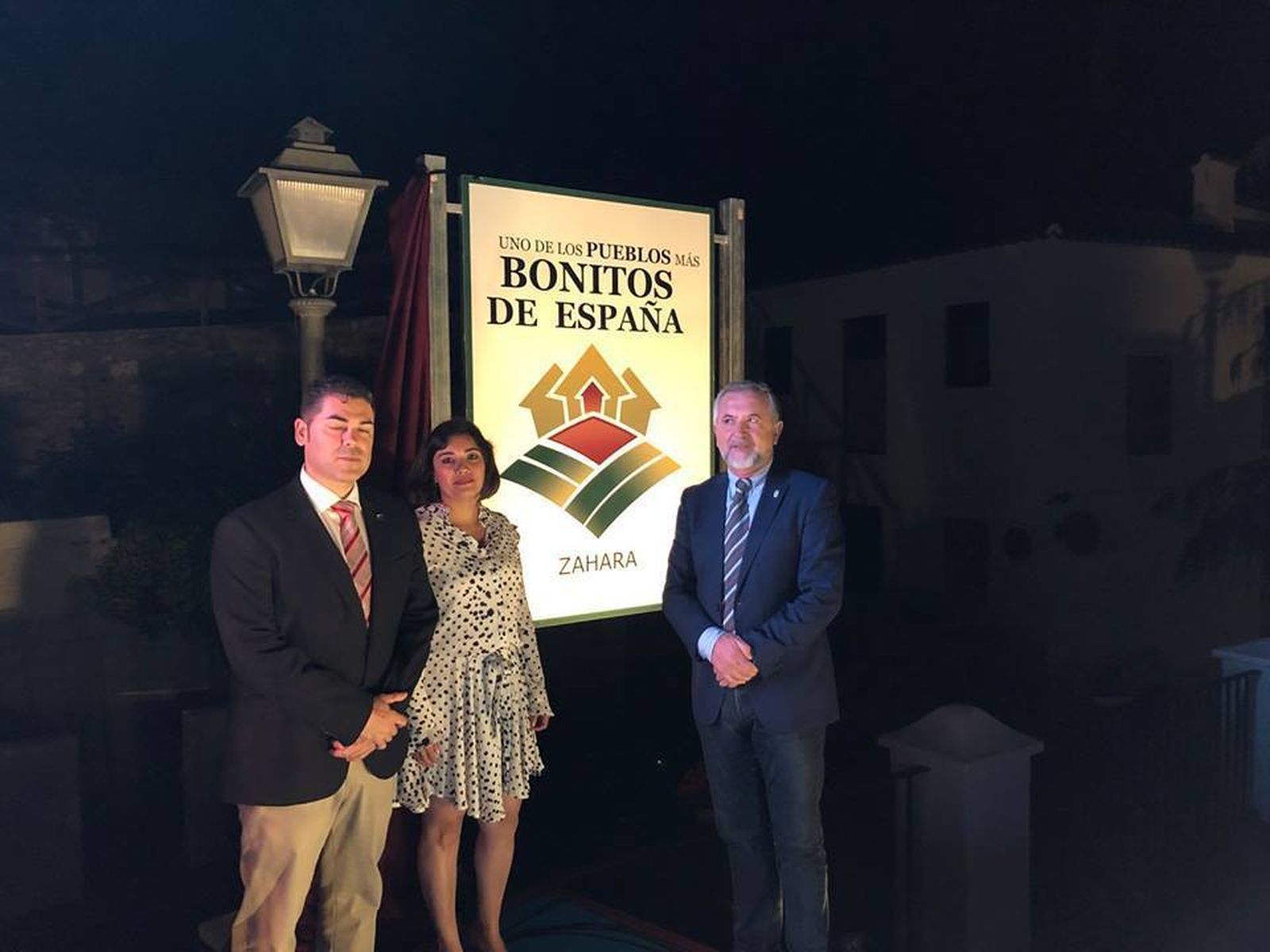 Los responsables institucionales junto al cartel de la declaración de Pueblo Más Bonito de España.