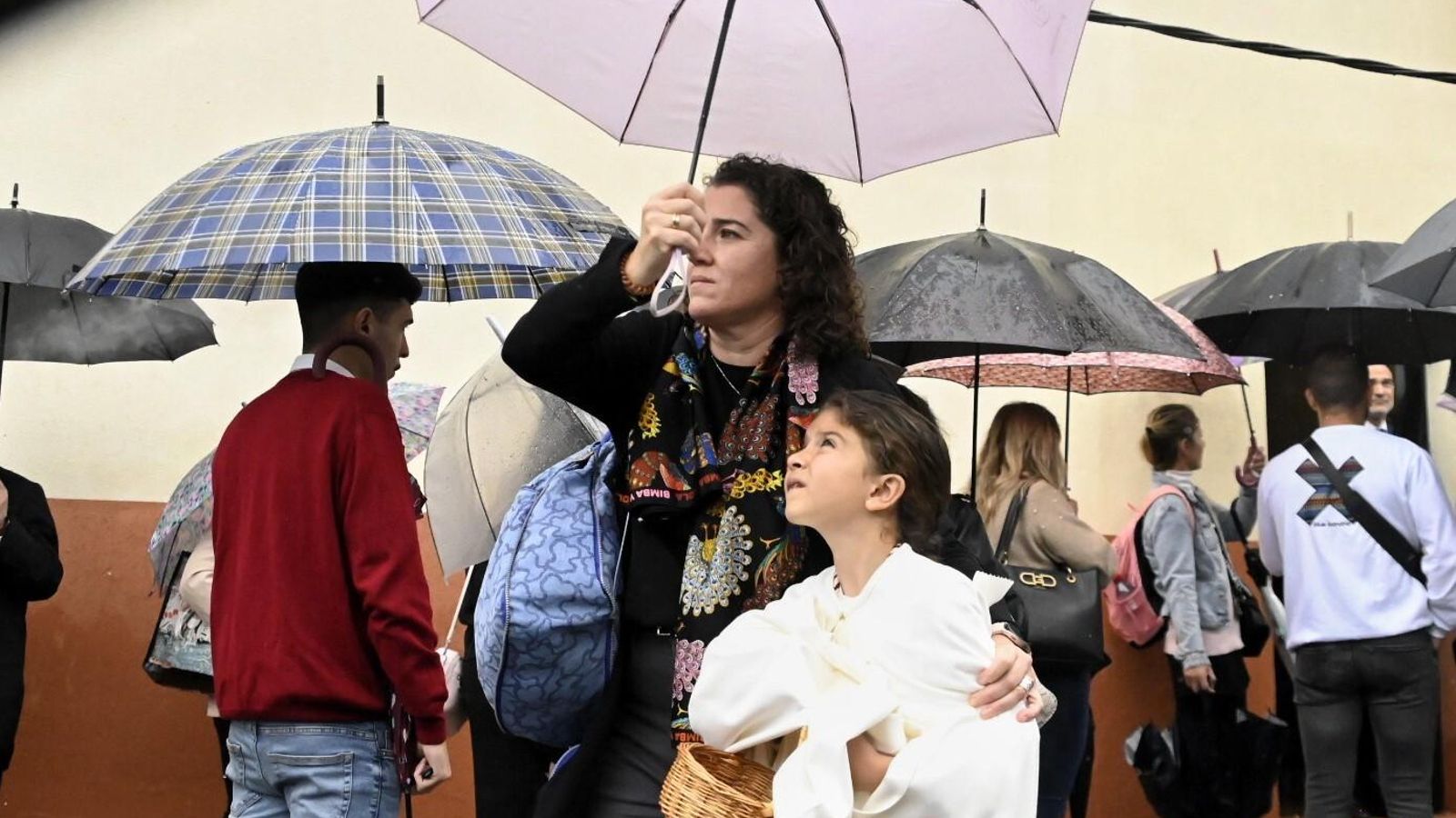 Una mujer protege con un paraguas a una niña en la salida de La Merced.