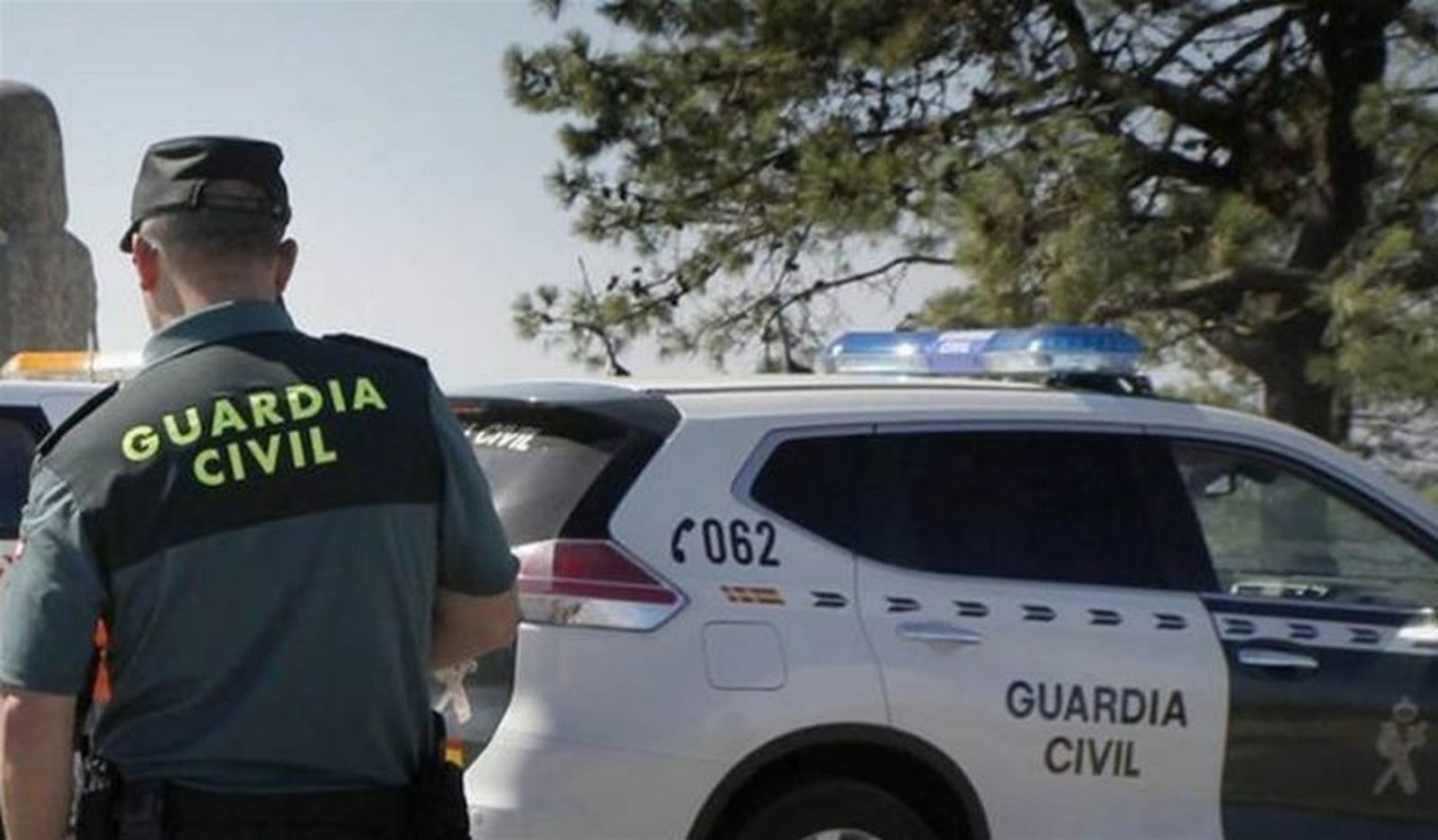 Un agente de la Guardia Civil ante un patrullero.