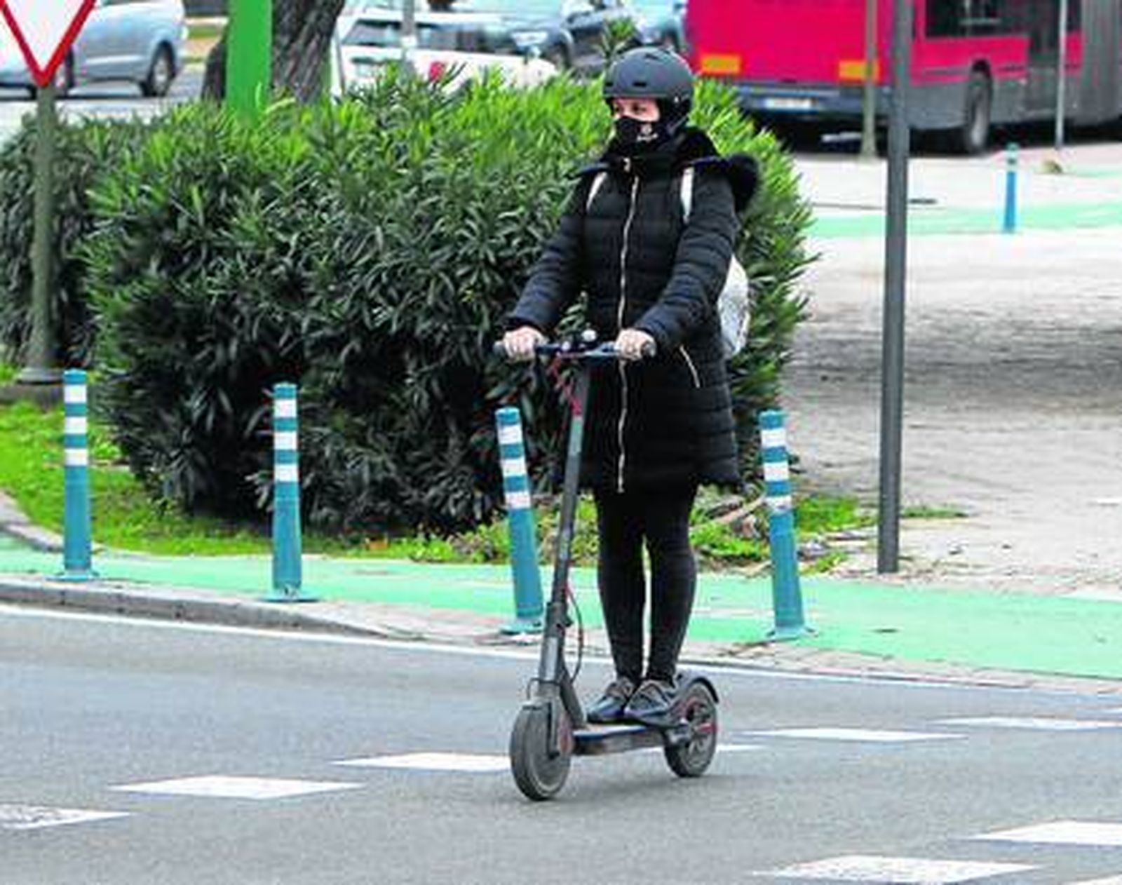 Una joven cruza un paso de peatones sobre un patinete.