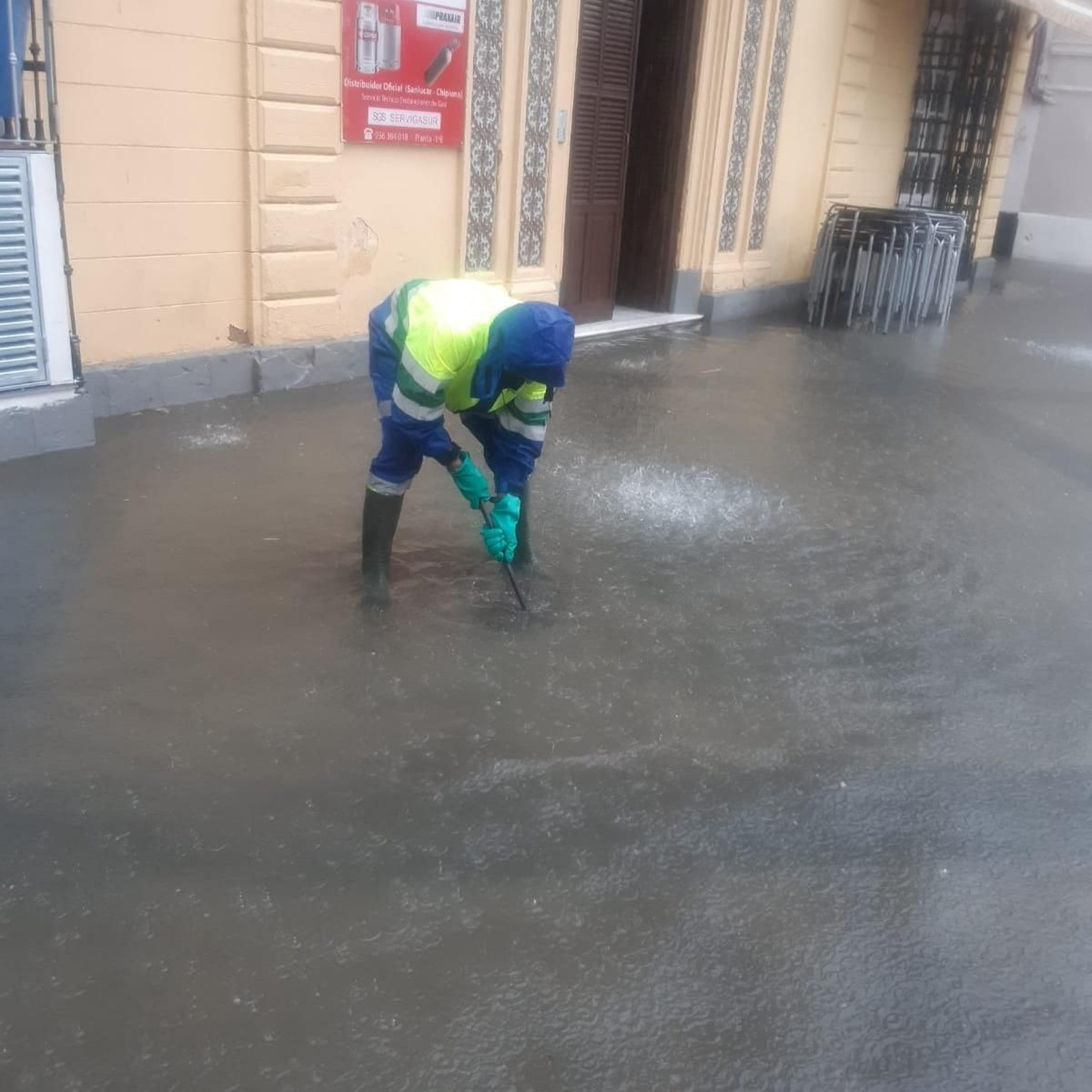 Un trabajador municipal trata de levantar una alcantarilla para evacuar el agua.