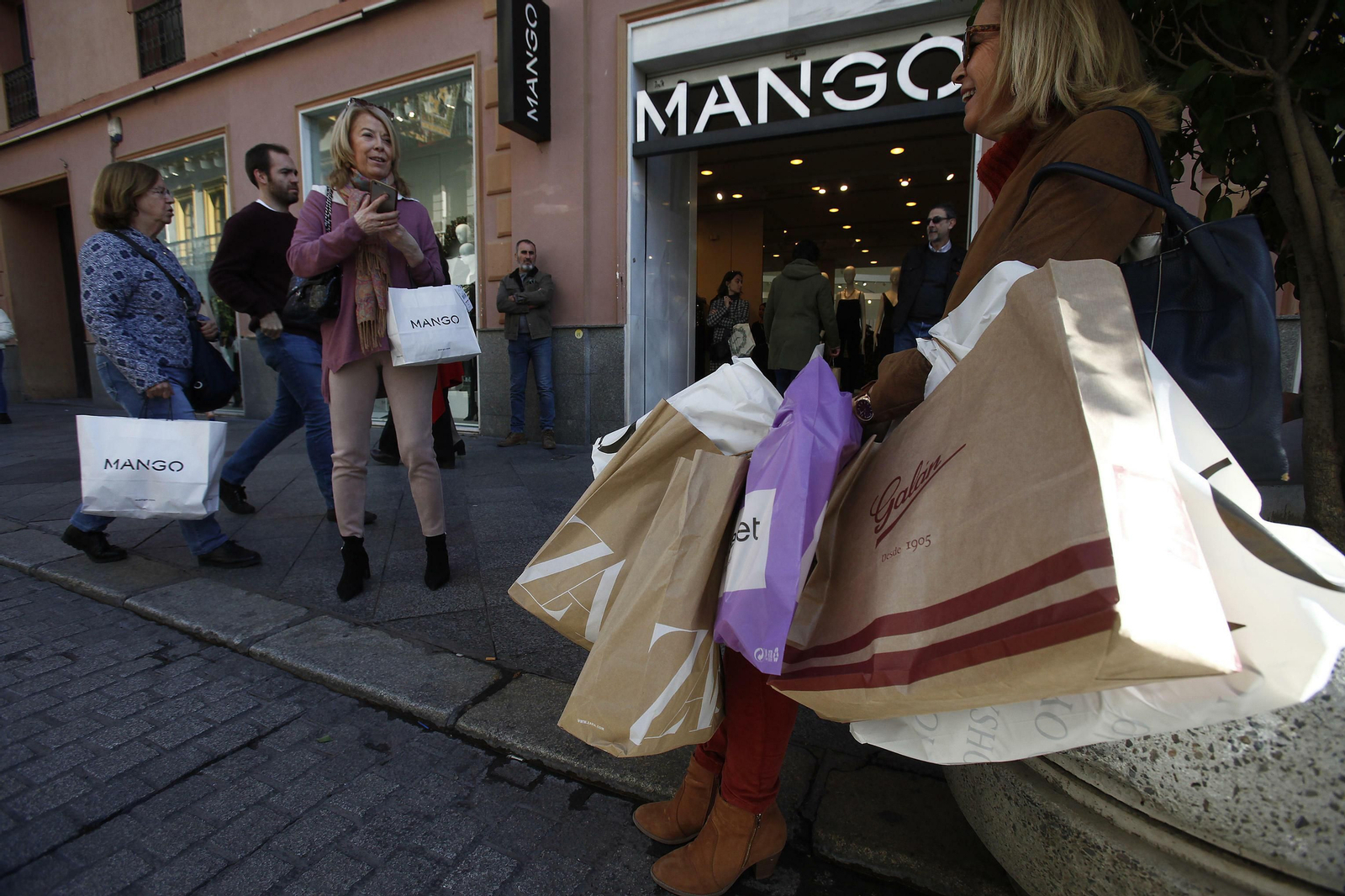 Varias personas cargadas con bolsas de las últimas compras navideñas.