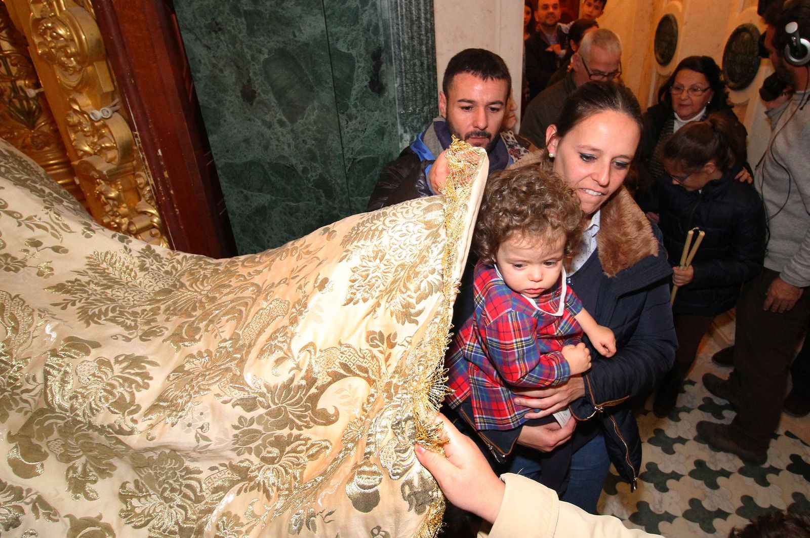 Fotografía de archivo del año 2018. Una madre bendice a su pequeña pasándola por el manto de la Virgen