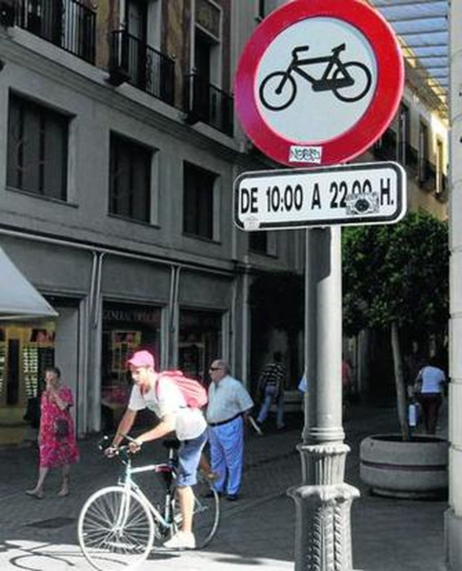 Un ciclista se sube a la bici al salir de Tetuán, donde permanece la placa que prohíbe circular en bici.