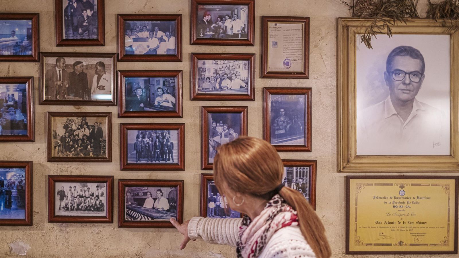 Eva Zamorano muestra las imágenes históricas de la taberna que cuelgan de una de las paredes del local.