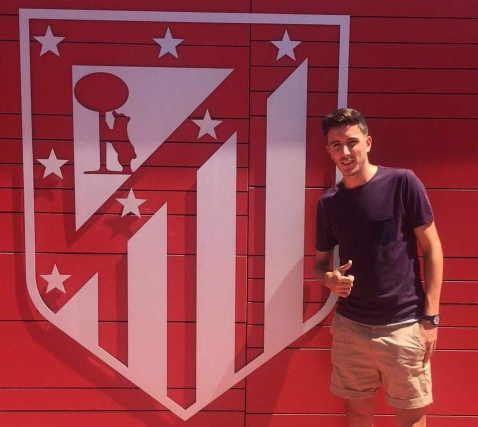 Alberto Ródenas posa ante el escudo del Atlético tras firmar como colchonero.