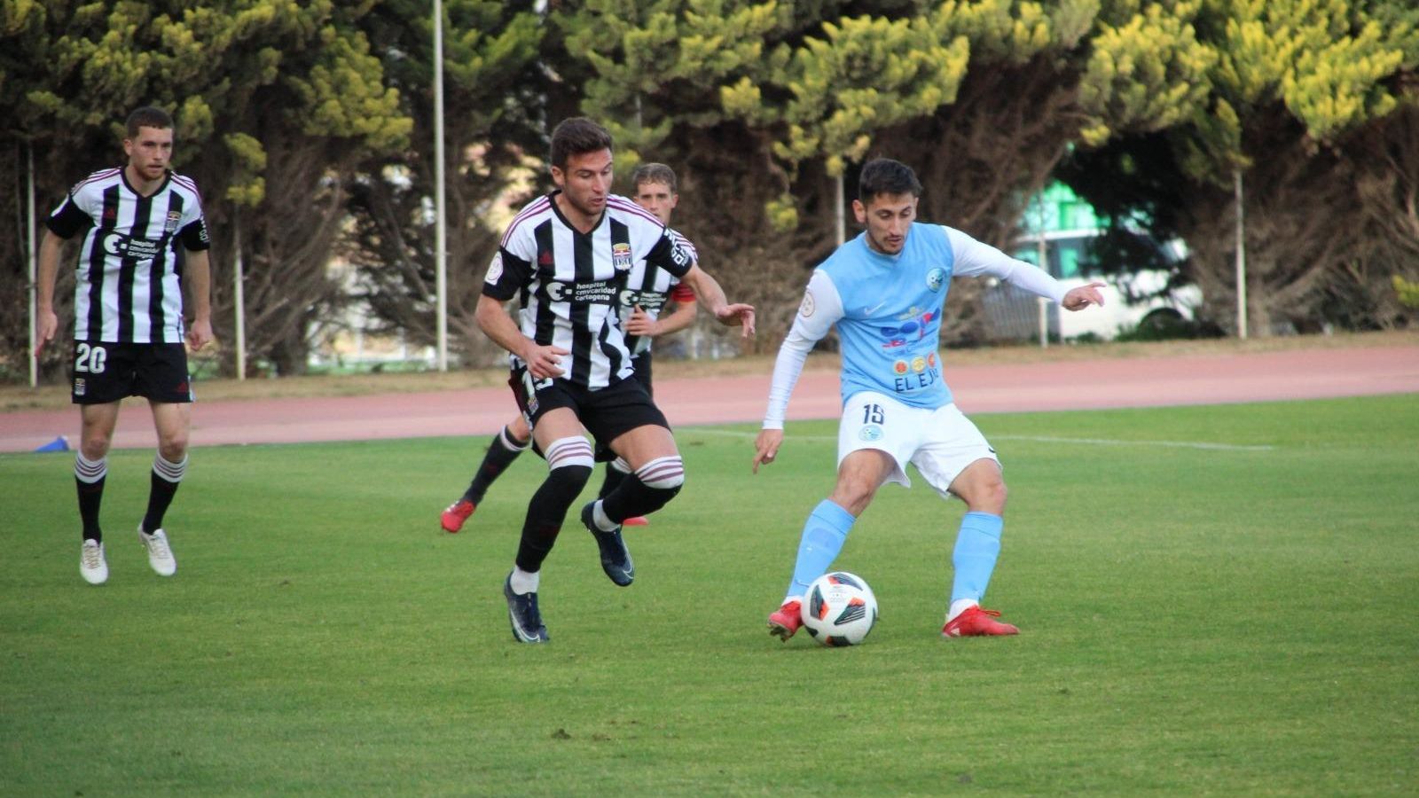 Juanje se dispone a ejecutar un pase ante la presión de un futbolista del filial albinegro.