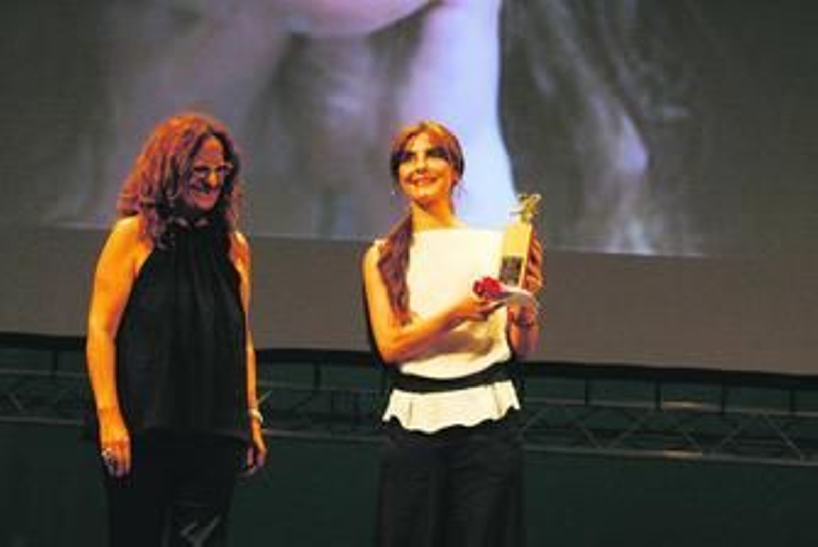 La actriz Ana Fernández muestra el premio que momentos antes le había entregado la coordinadora de Alcances, Vega López.