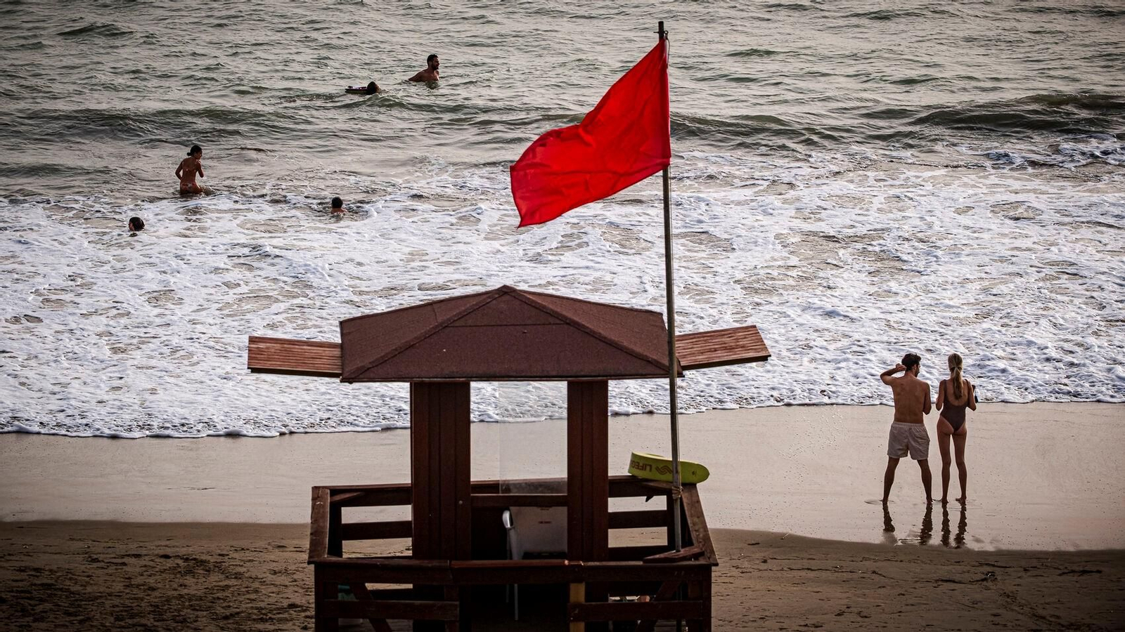 Un grupo de personas se bañan en una playa de Cádiz con bandera roja durante el último episodio de mar de fondo.