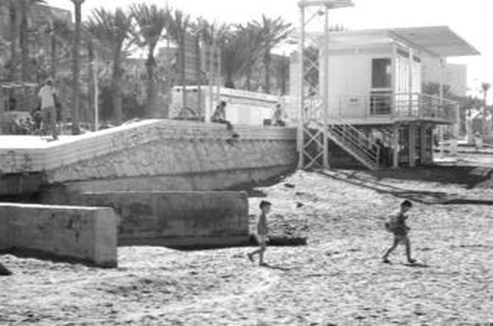Unos niños pasan junto a la boca de saneamiento que llega hasta la playa de El Zapillo.