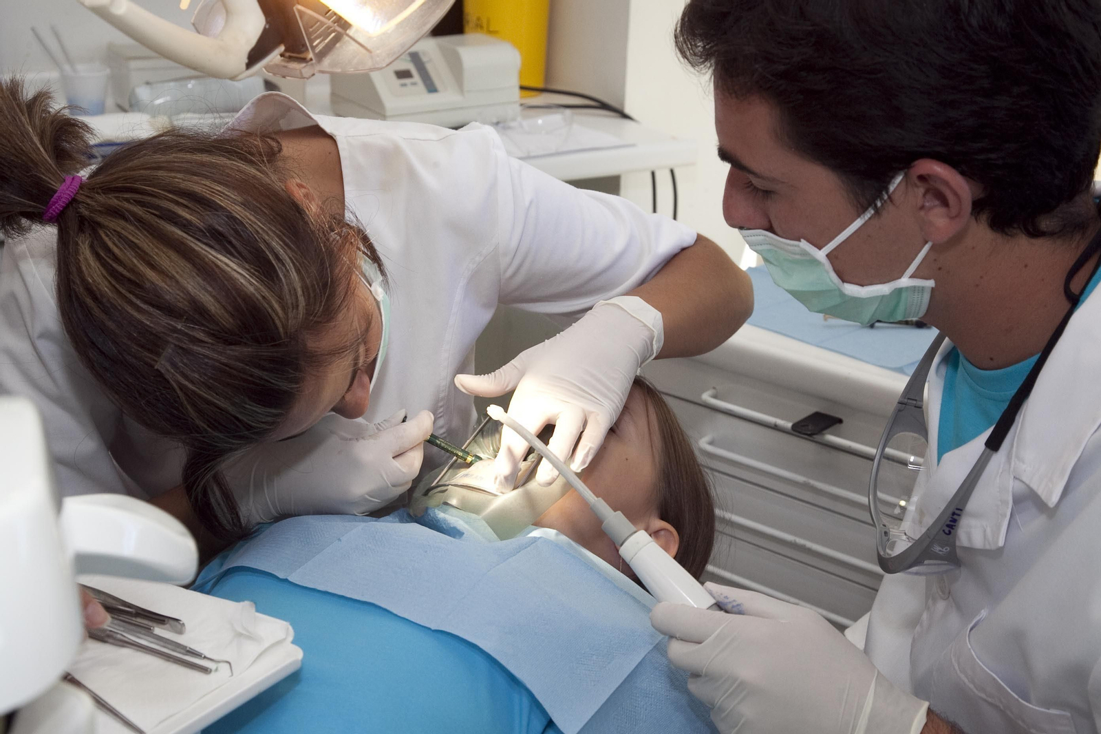Dos dentistas atienden a un niño en consulta.