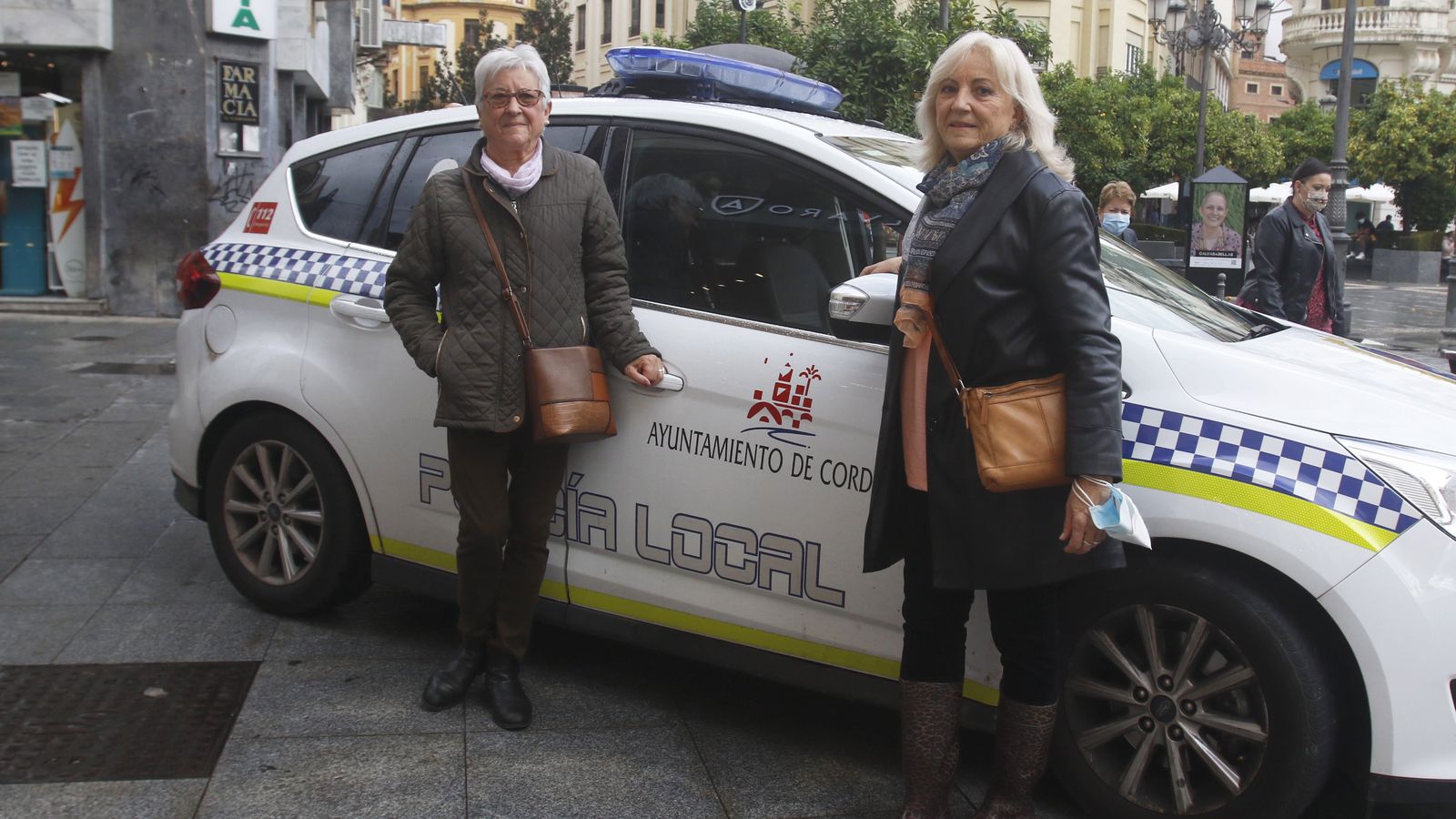 Lola y Delfina posan frente a un coche de la Policía Local de Córdoba.