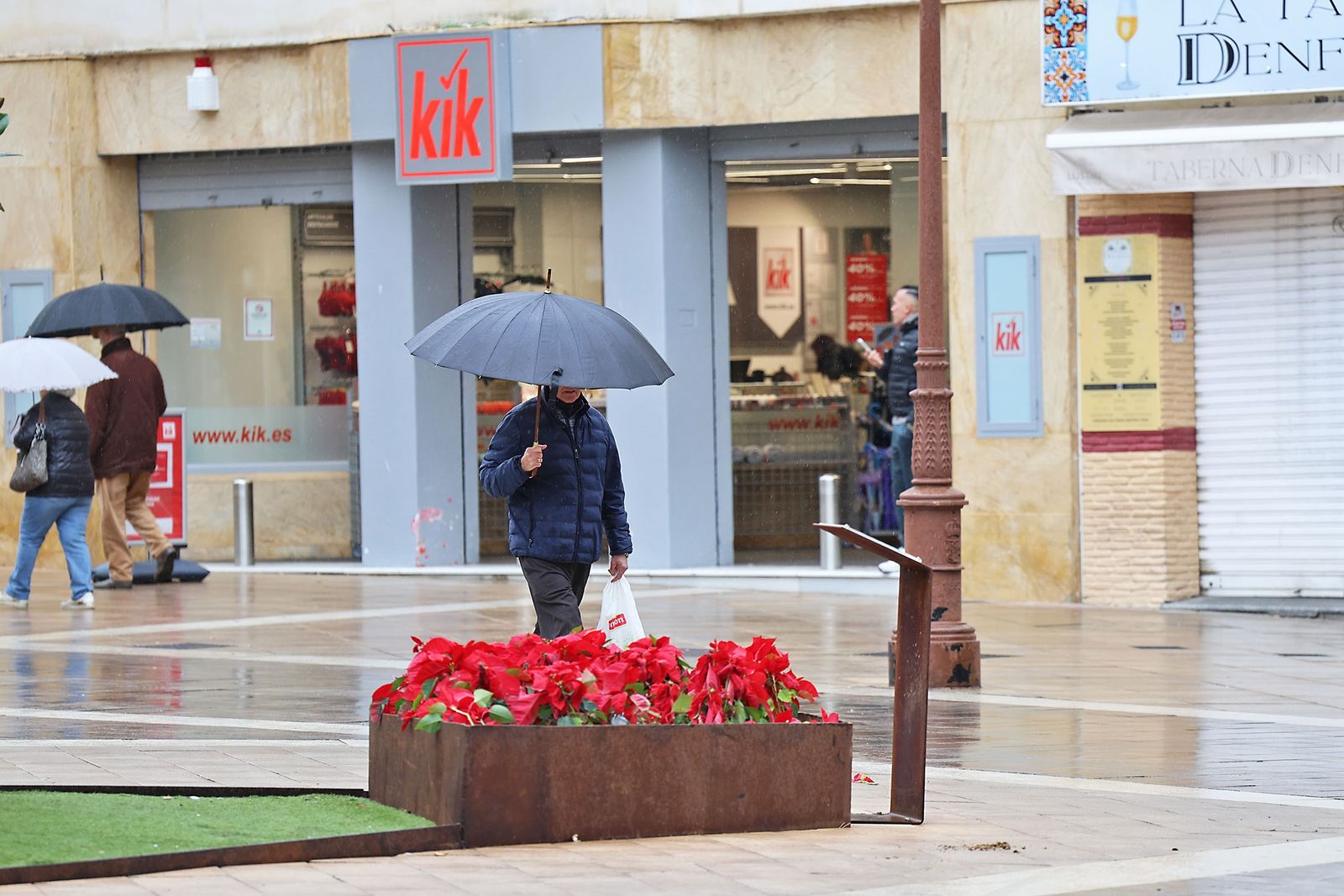 Varias personas pasean con paraguas en Huelva un día de lluvia.