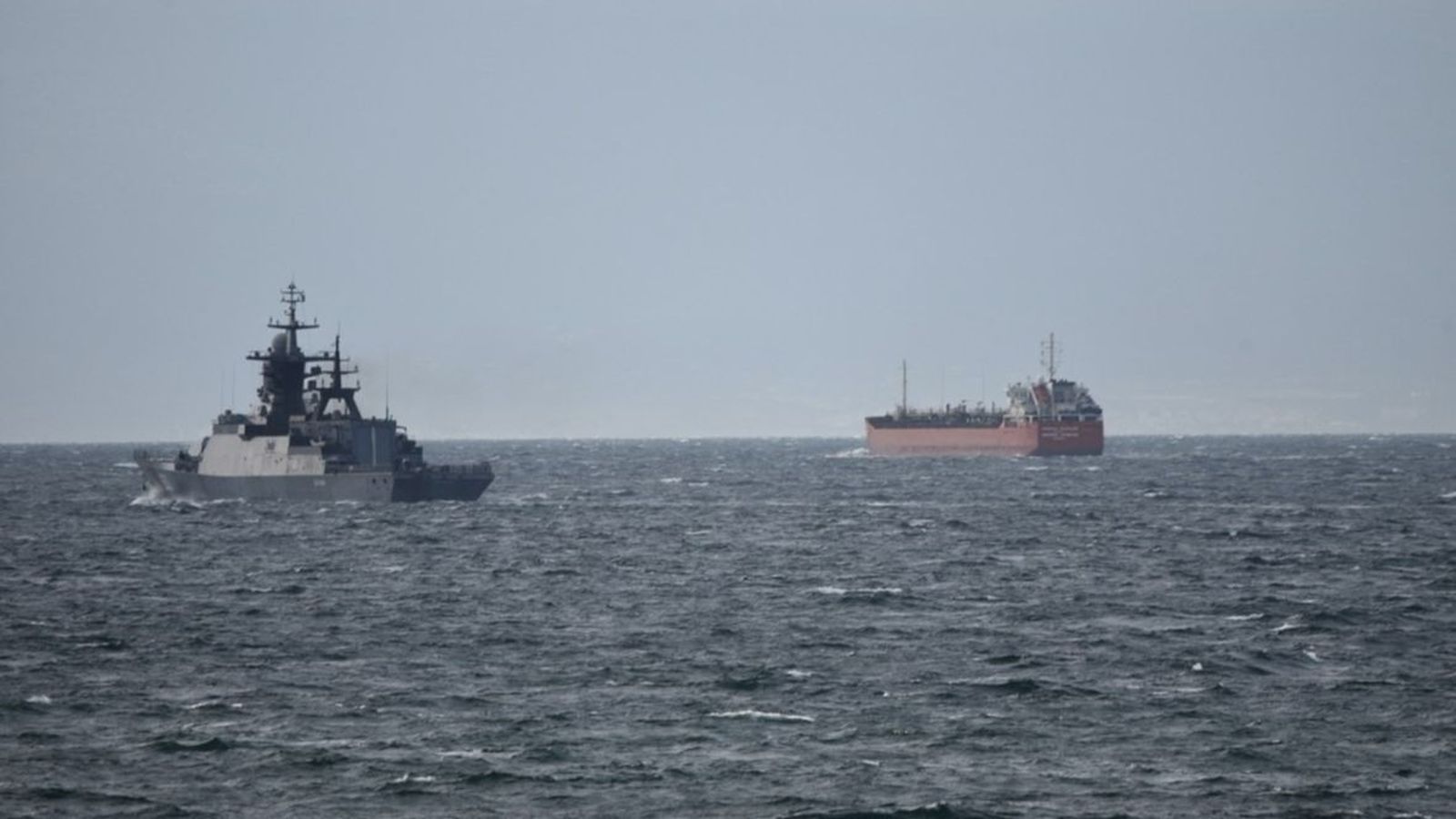 Un buque milita junto a un mercante en las aguas del Estrecho.