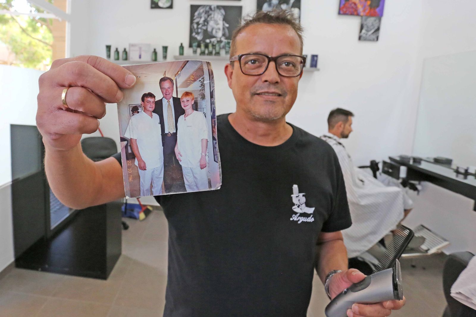 Miguel Argudo muestra la fotografía que se hizo en 1995 con George H. W. Bush durante su estancia como peluquero en Barcelona.