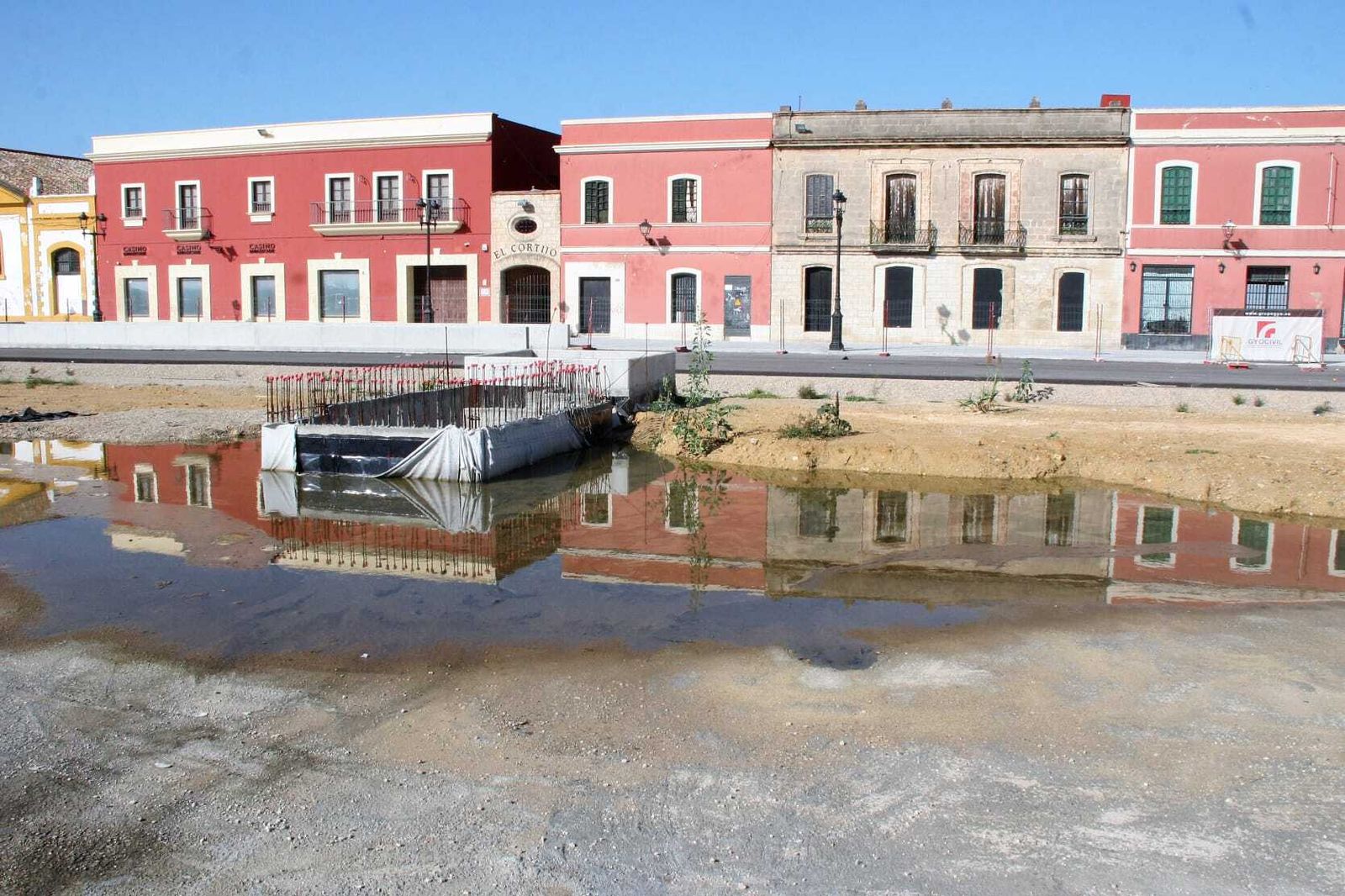 Los edificios de Pozos Dulces se reflejan en el agua de las últimas lluvias, entre ellos el Casino Bahía de Cádiz, que aguarda el fin de la obra para su traslado.