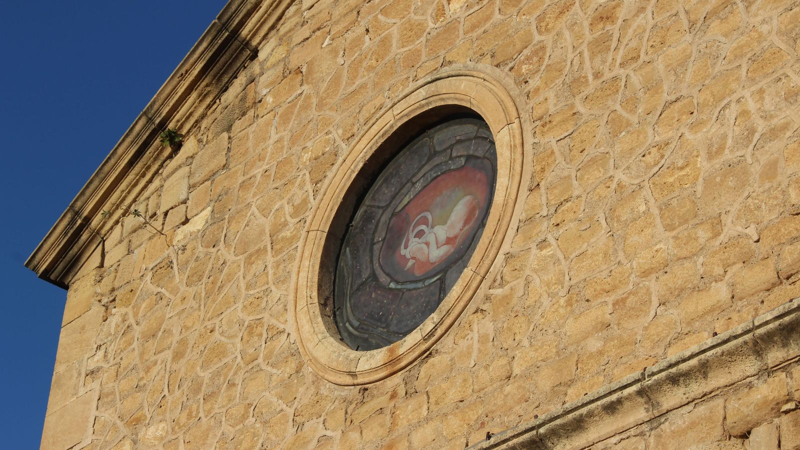 Exterior de la nave lateral de la iglesia de Turre, con la vidriera del feto.