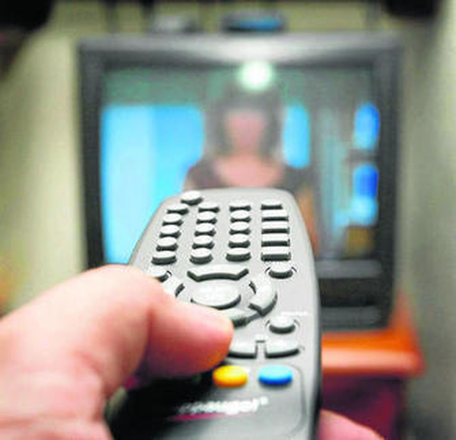 Una persona apunta con un mando a distancia a la televisión.
