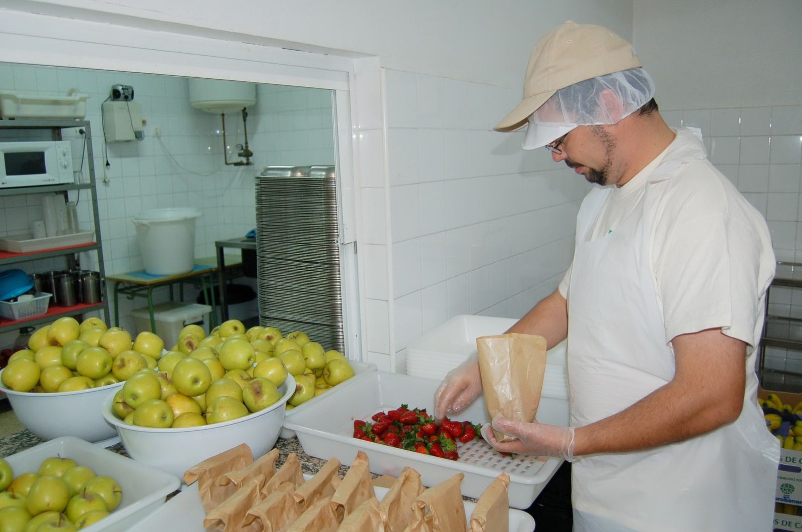 Empleado de una empresa de catering que sirve a un comedor.