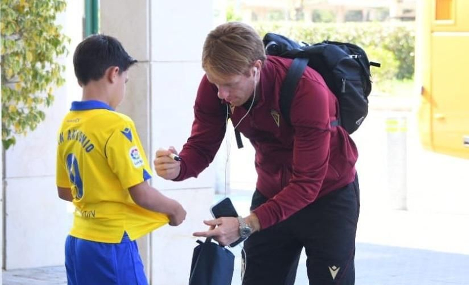 Álex deja su rúbrica en la camiseta de un joven seguidor a la entrada del Aeropuerto de Jerez.