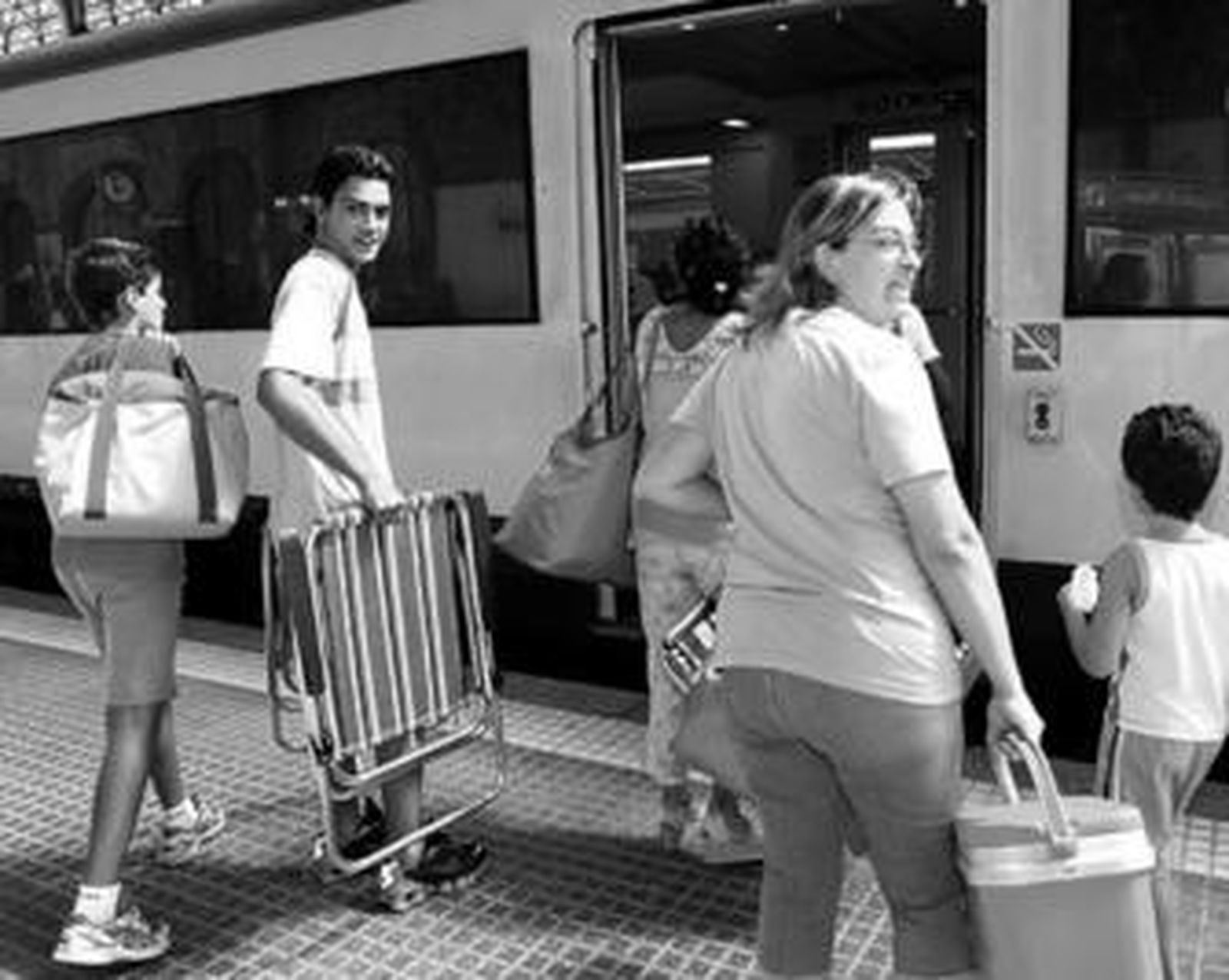 Una familia sube al tren preparada para ir a la playa.