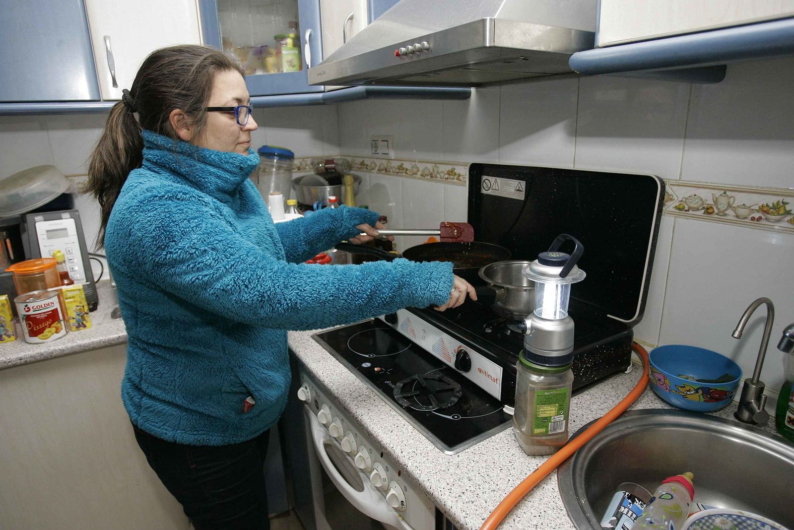 Una mujer cocina sin luz en casa.