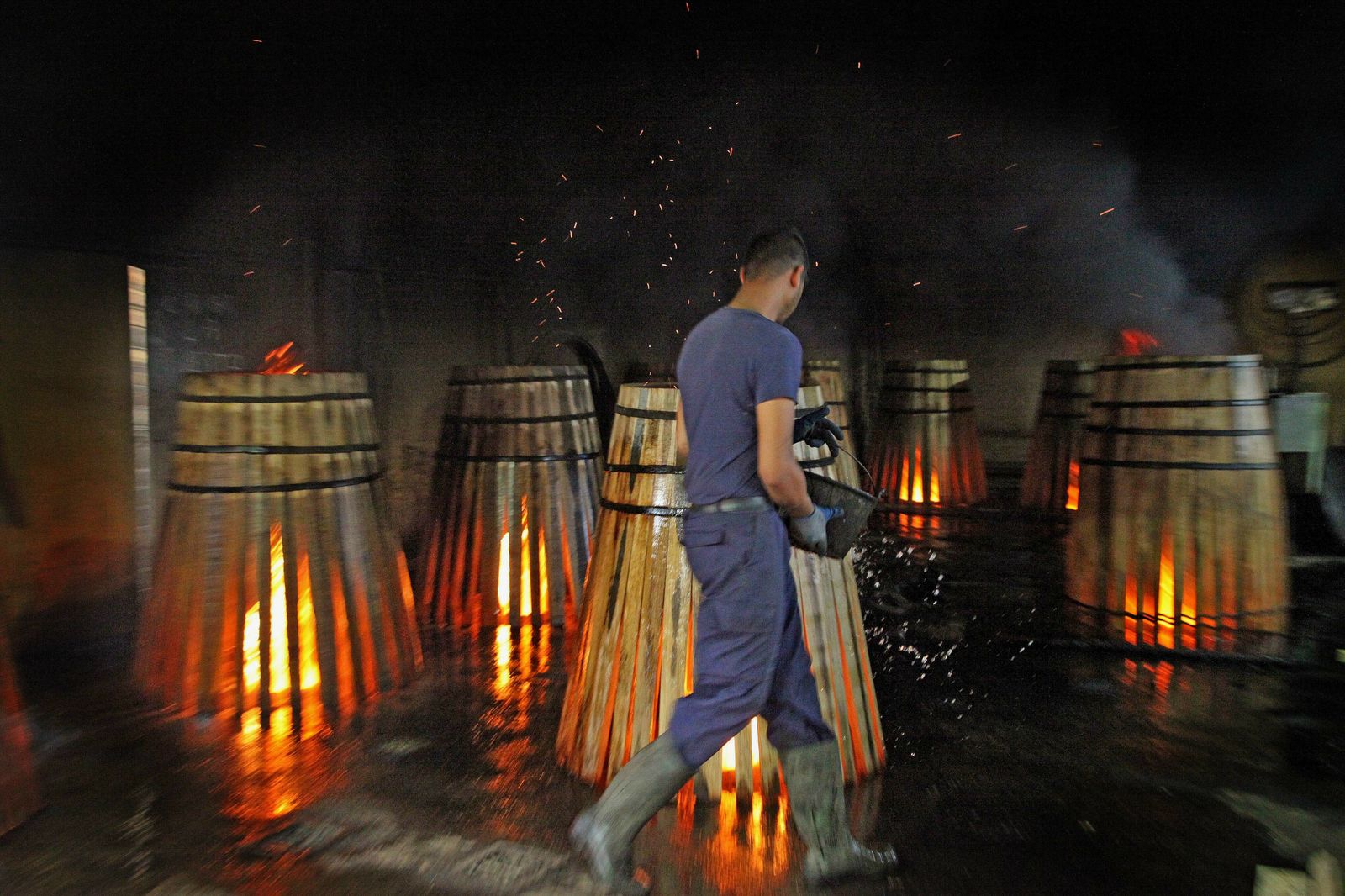 Un trabajador de una tonelería jerezana refresca las duelas de las botas antes de darles forma.