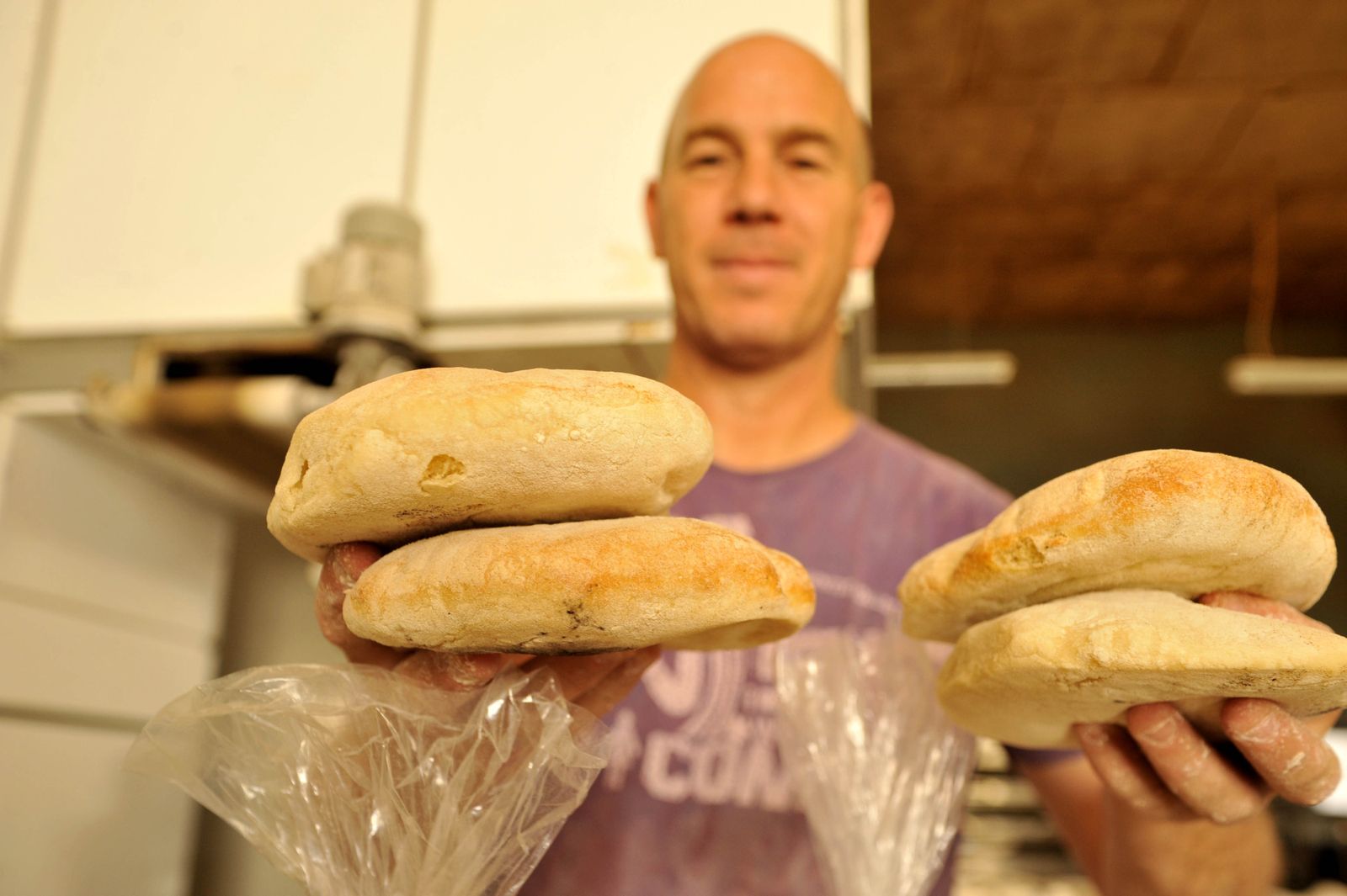 Uno de los trabajadores de la panificadora La Paz sosteniendo varios molletes de Espera, productos demandados en los mercados.