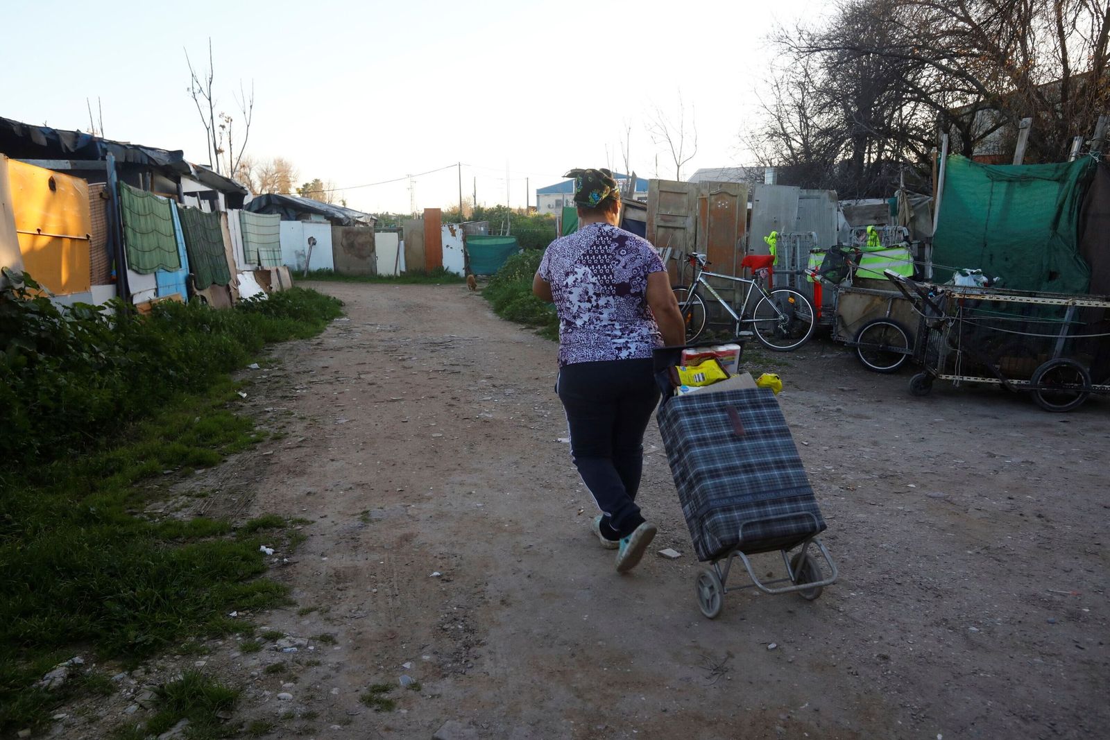 Una mujer lleva un carrito de comida a su vivienda en el asentamiento de Camino Carbonell