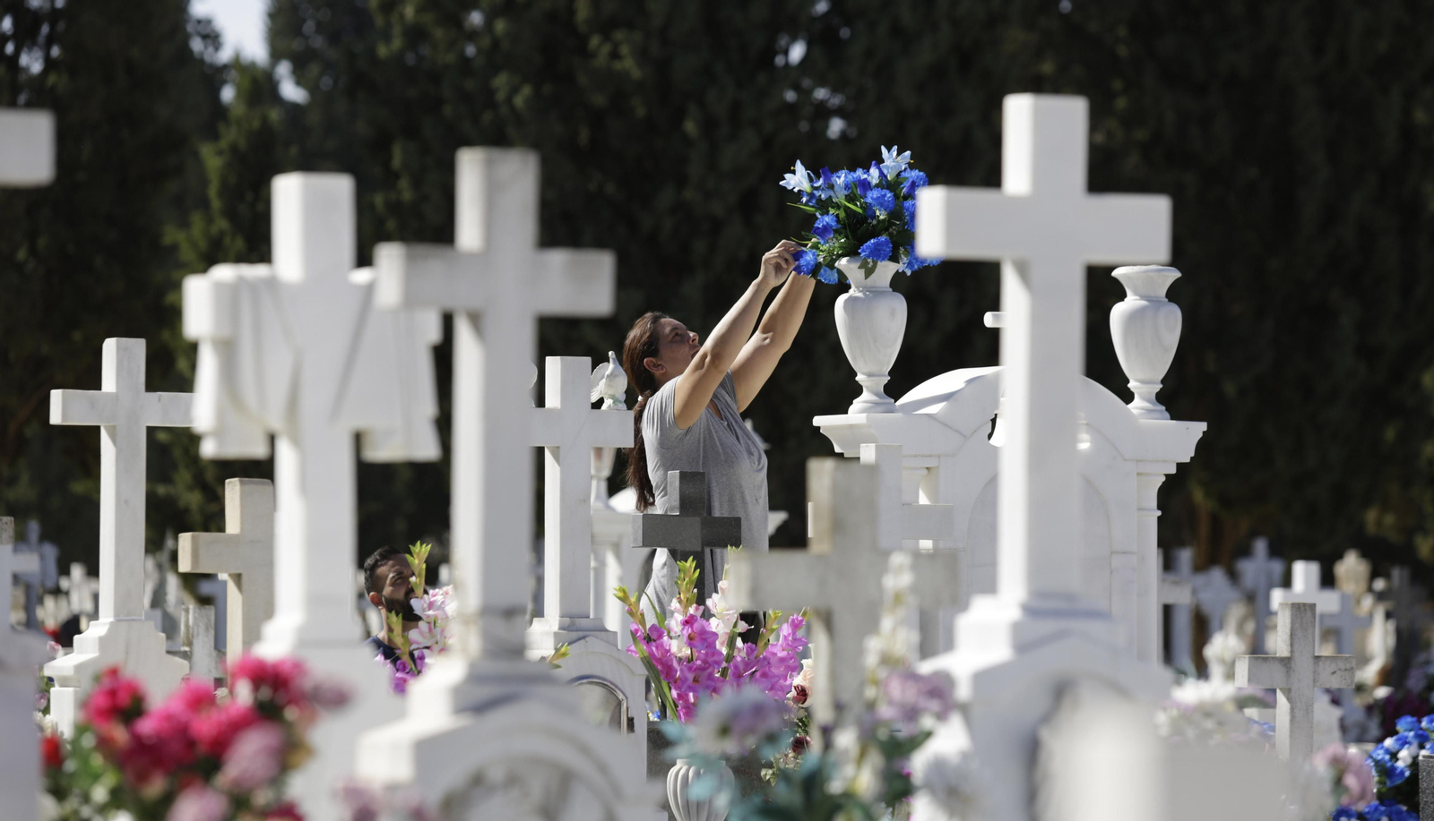 Una mujer coloca flores en una tumba, práctica habitual en vísperas de Todos los Santos.