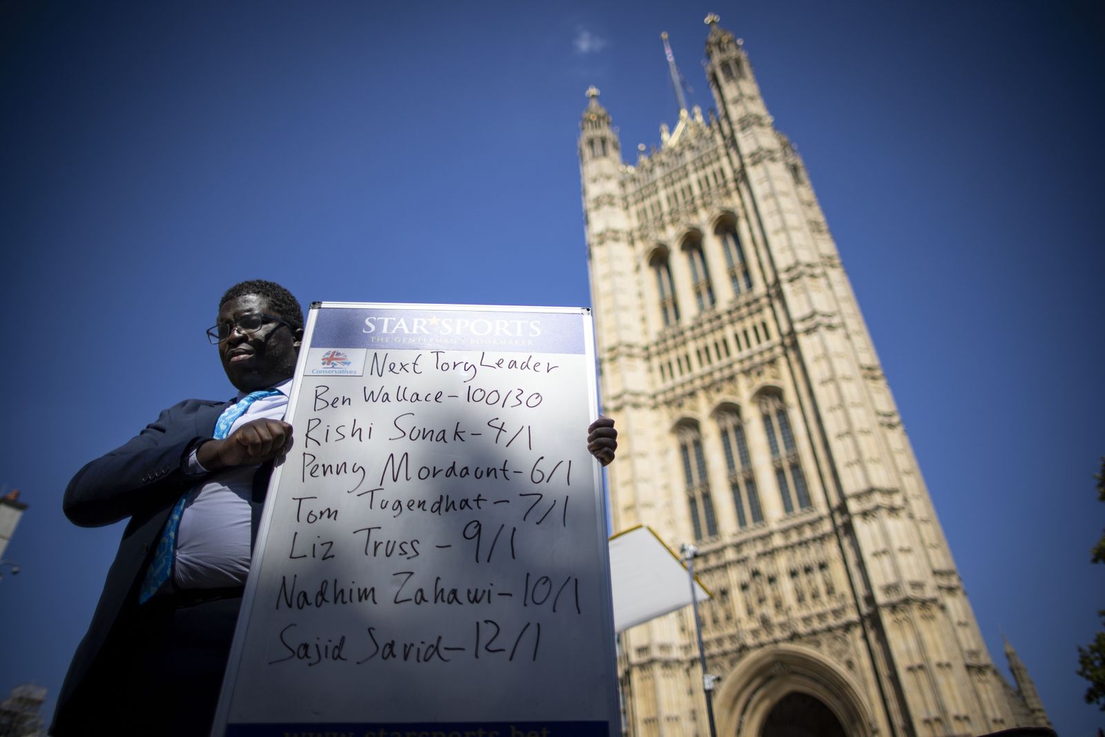 Un hombre sostiene una pizarra con las apuestas sobre quién sustituirá a Johnson.