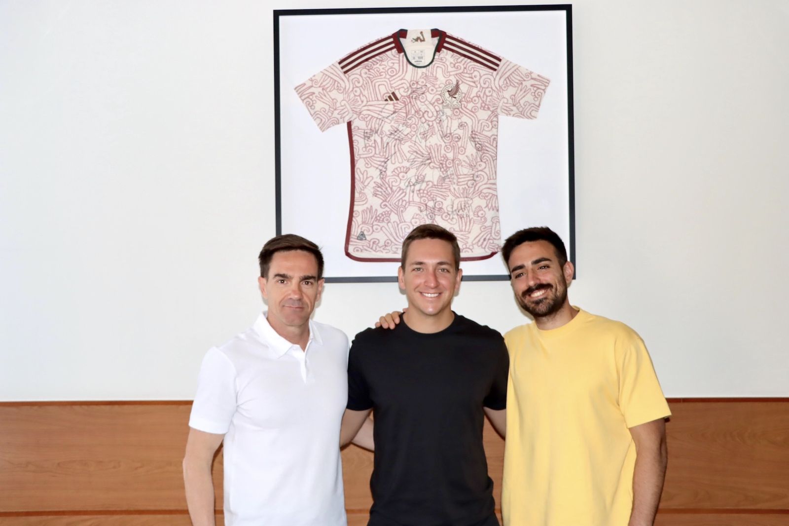 Andrés López (centro), junto al decano de Educación, Manuel Rodríguez (derecha), y su excompañero de promoción y codirector de su tesis, Andrés Baena, se fotografían junto a la camiseta de la selección mexicana de fútbol.