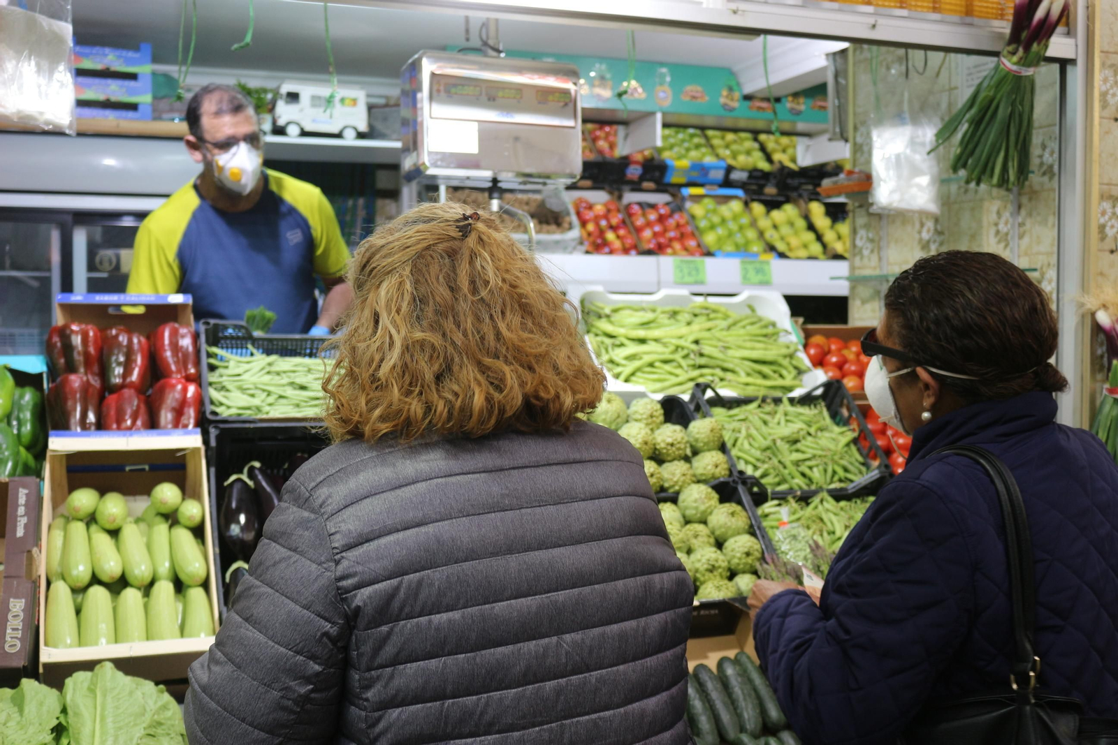 Clientas y detallistas utilizando la mascarilla en uno de los puestos del Mercado