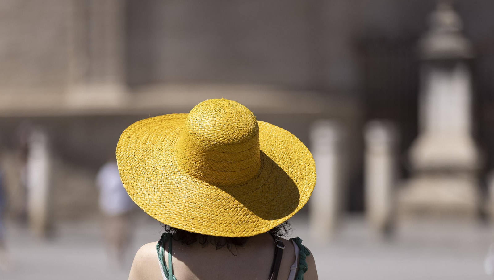 Una turista se cubre del sol con un sombrero.