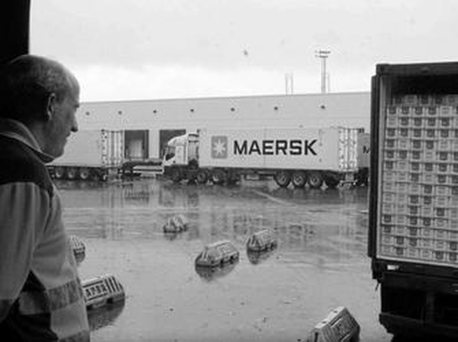 Un trabajador del PIF mira un contenedor reculando hacia una de las bocas del servicio de inspección, mientras otro se marcha.