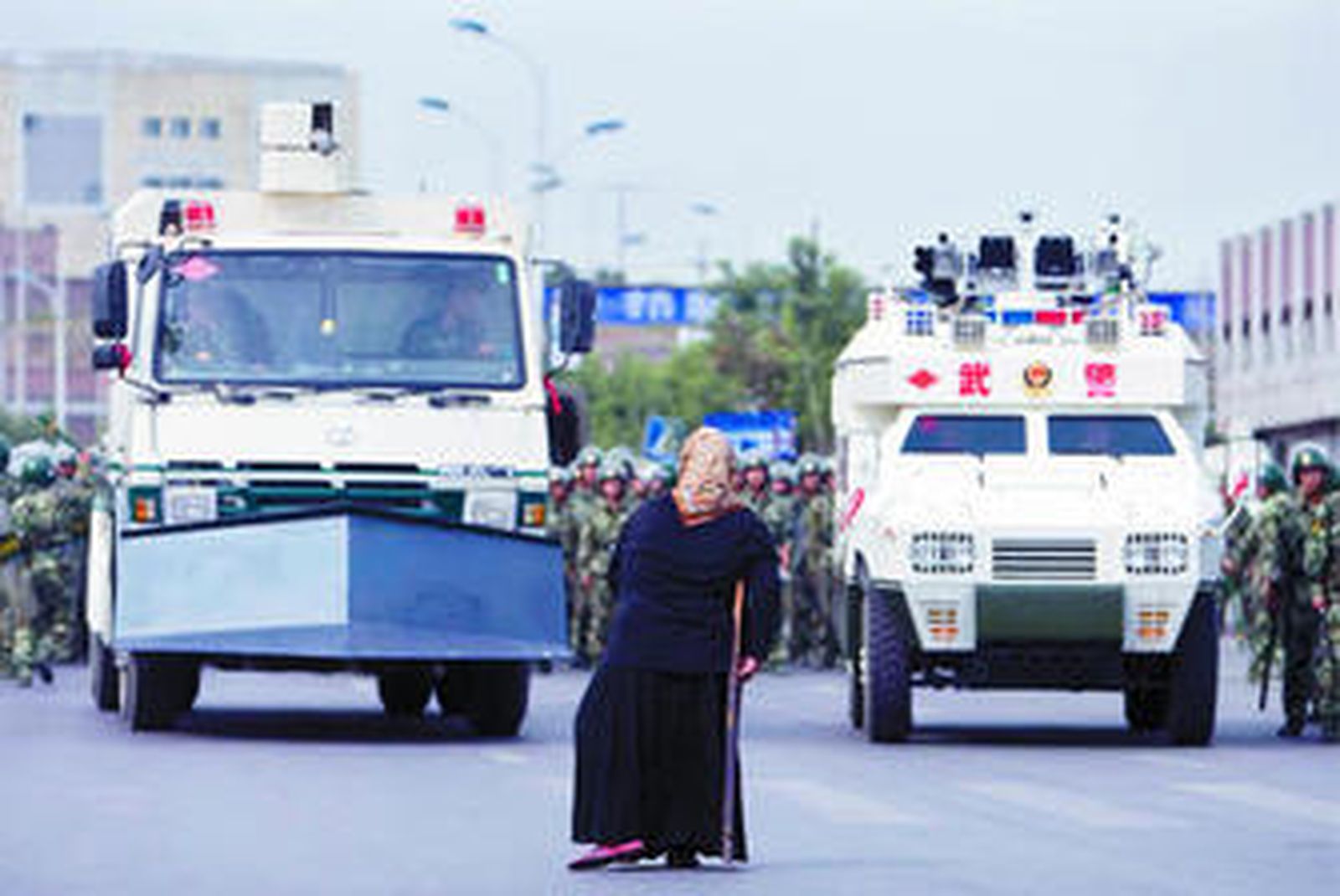 Una mujer de etnia uigur pasa delante de un vehículo militar blindado en Urumqi.