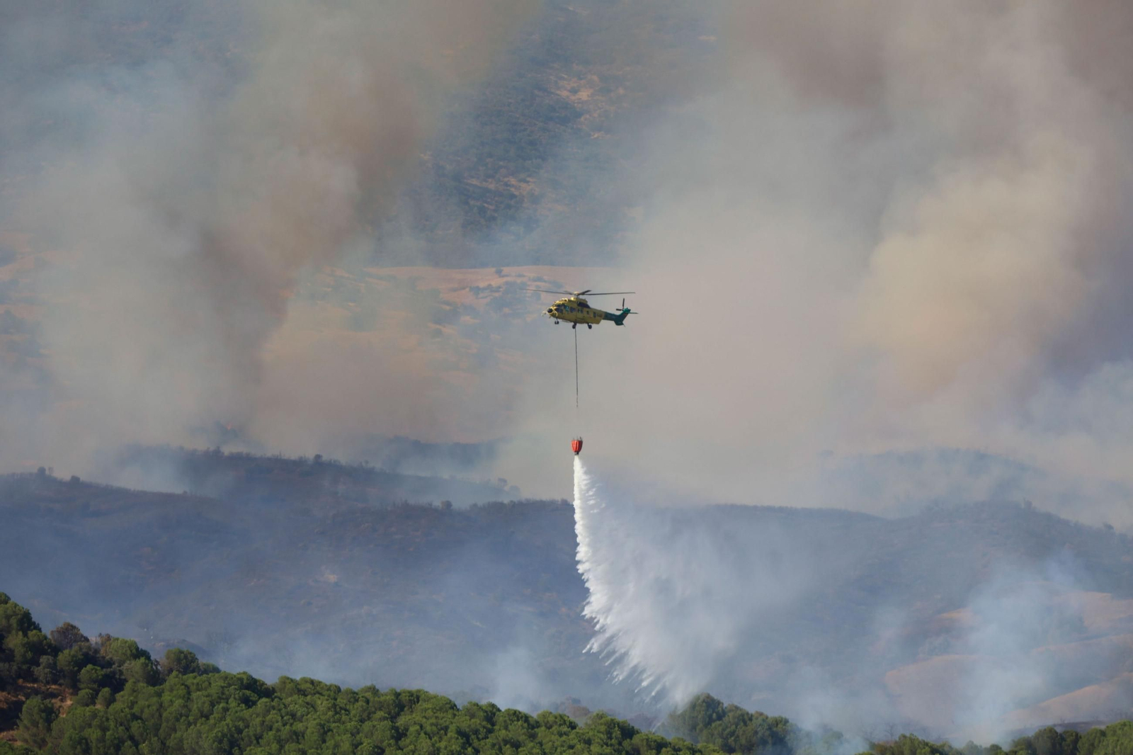 Un helicóptero trabaja para extinguir las llamas en incendio forestal en el campo de tiro de la base militar de Cerro Muriano (Córdoba)