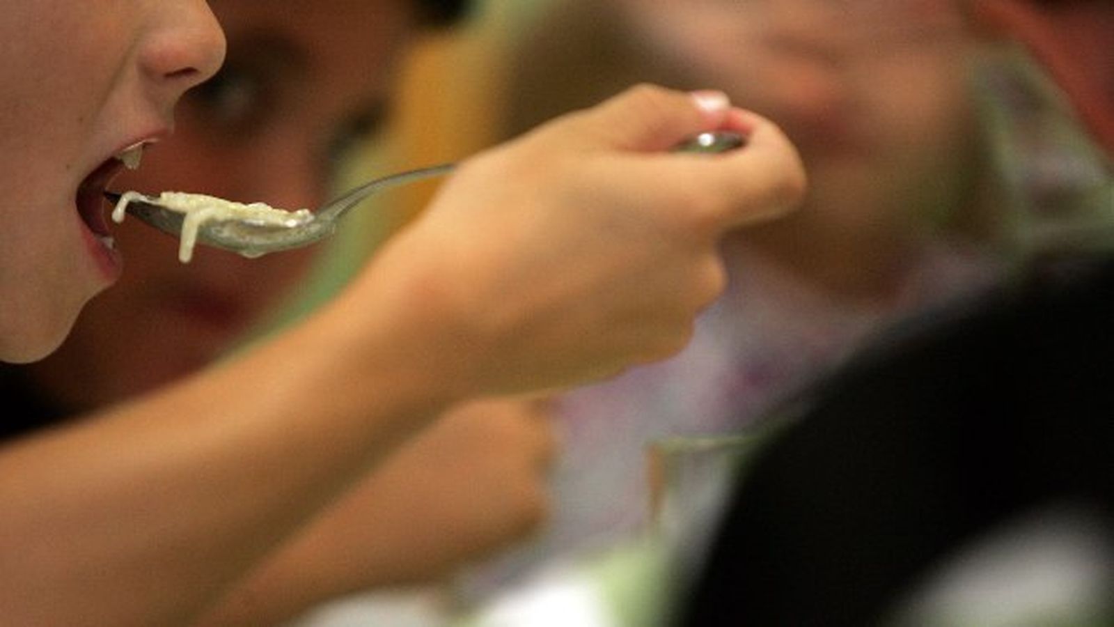 Un niño almuerza una sopa de fideos en un comedor social.