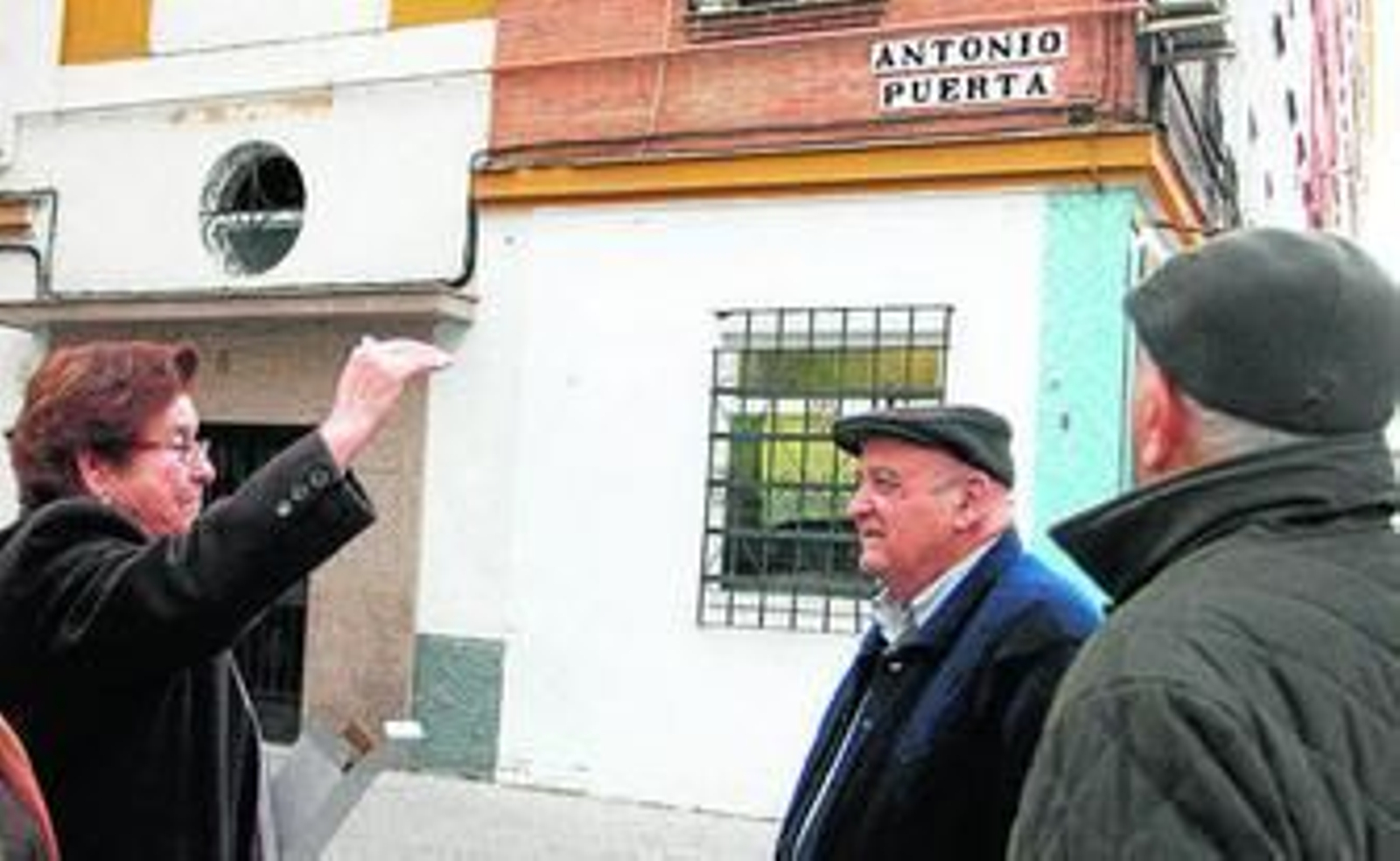 Tres personas dialogan en la esquina de la calle Antonio Puerta.