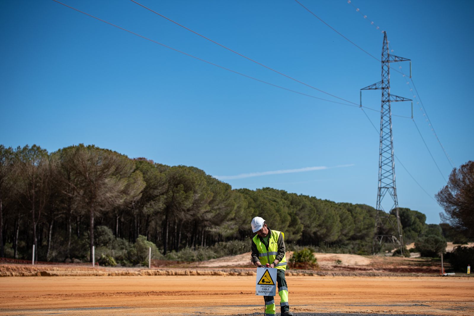 Un operario de Tragsa coloca un cartel de advertencia en la zona que sobrevuela la línea de alta tensión.
