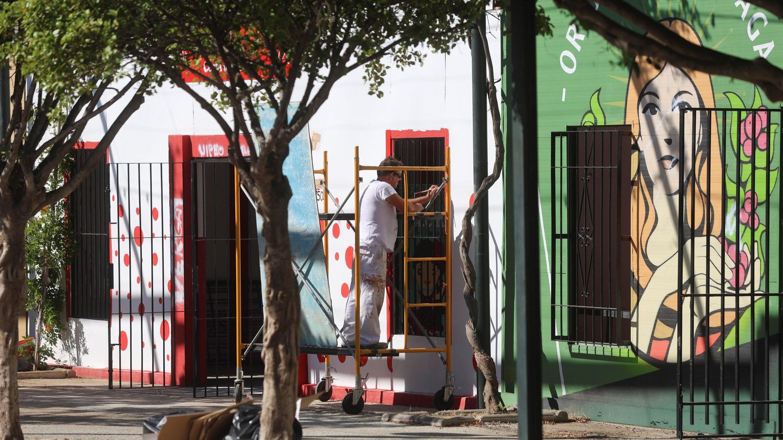 Un  peñista pinta su fachada en el Real de la Feria de Málaga.